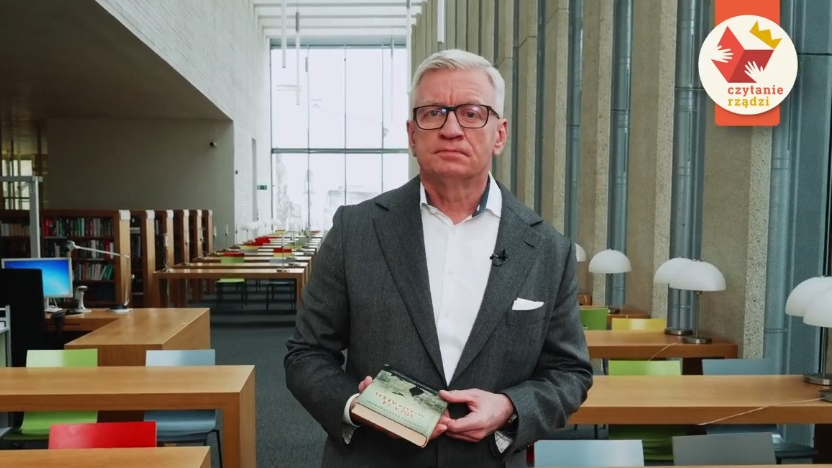 Na zdjęciu Jacek Jaśkowiak, prezydent Poznania, w bibliotece, z książką w ręku