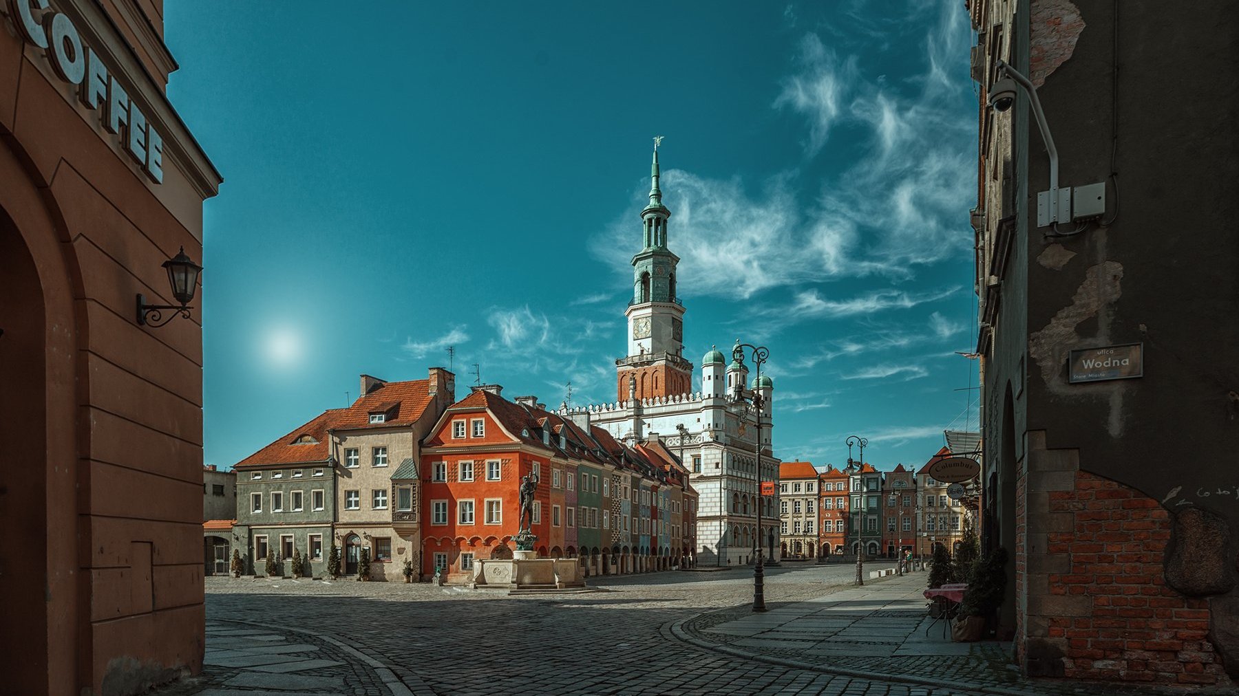 Zdjęcie przedstawia Stary Rynek w Poznaniu. W centralnej części zdjęcia widać kolorowe kamienice i wieże ratusza.