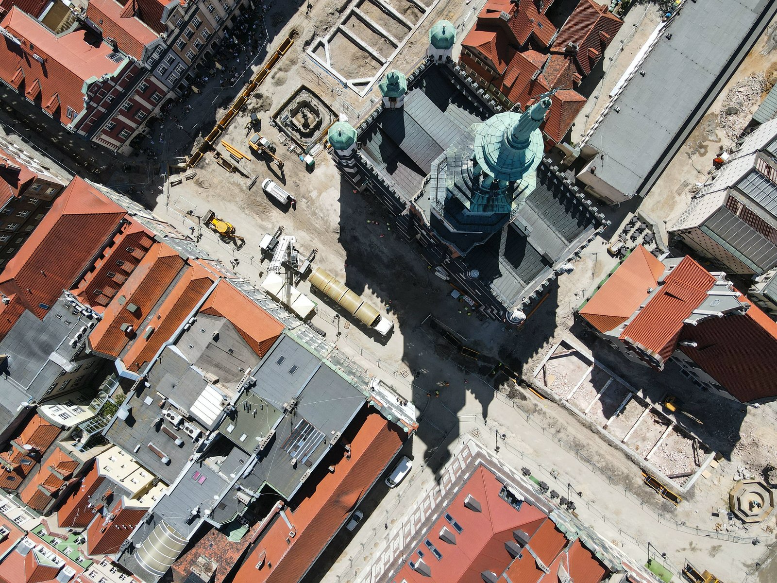 Zdjęcie przedstawia widok na Stary Rynek w Poznaniu z lotu ptaka. Na fotografii widoczen są dachy kamienic i sprzęt budowlany. - grafika artykułu