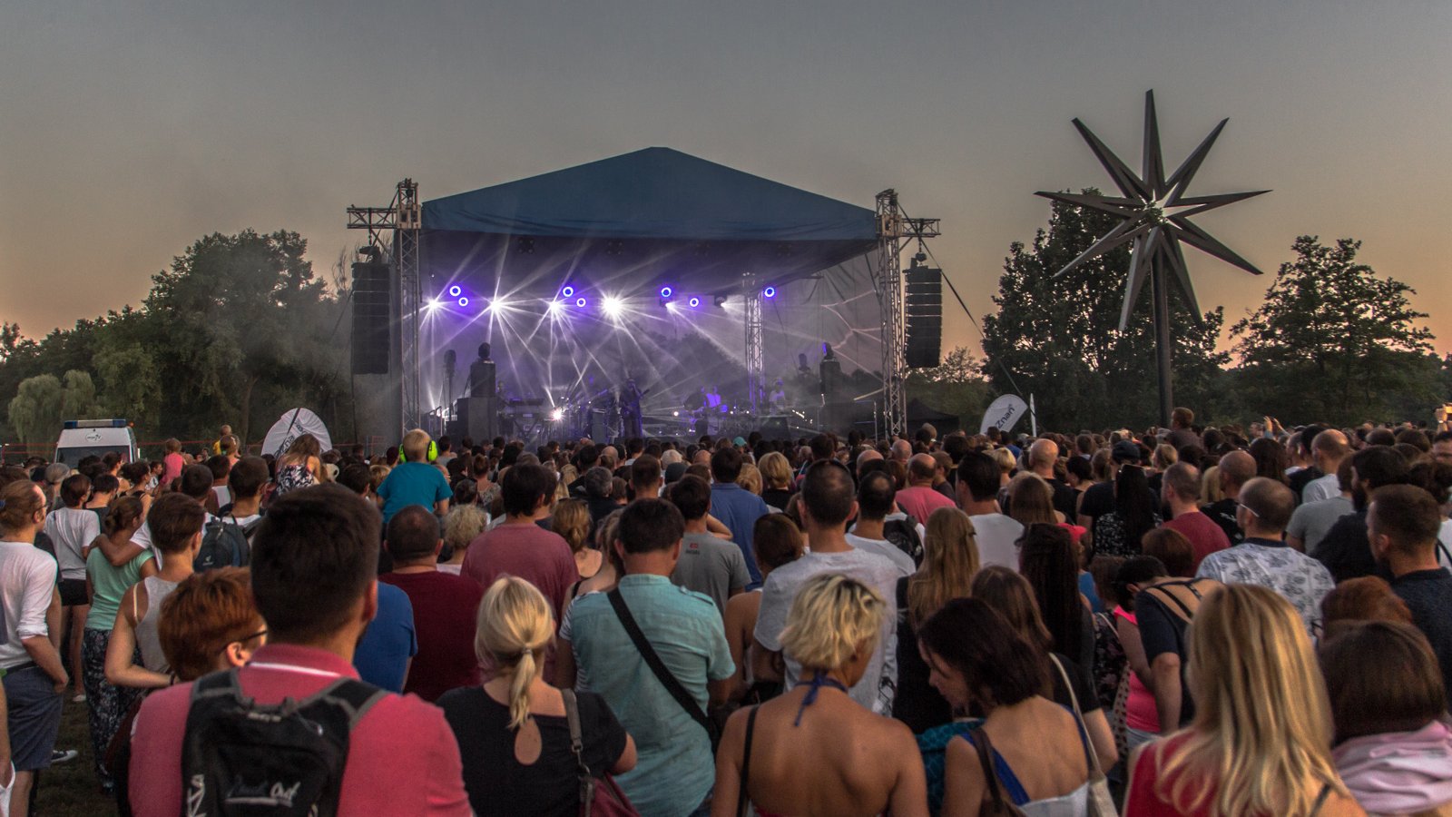 Na zdjęciu oświetlona scena, przed nią dużo młodych ludzi