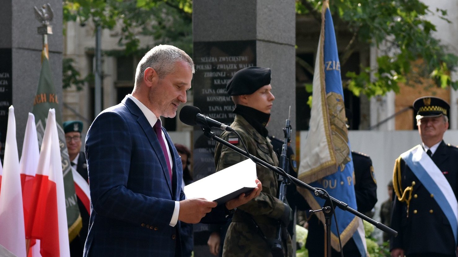 Na zdjęciu Jędrzej Solarski, zastępca prezydenta miasta, przy mikrofonie, pod pomnikiem