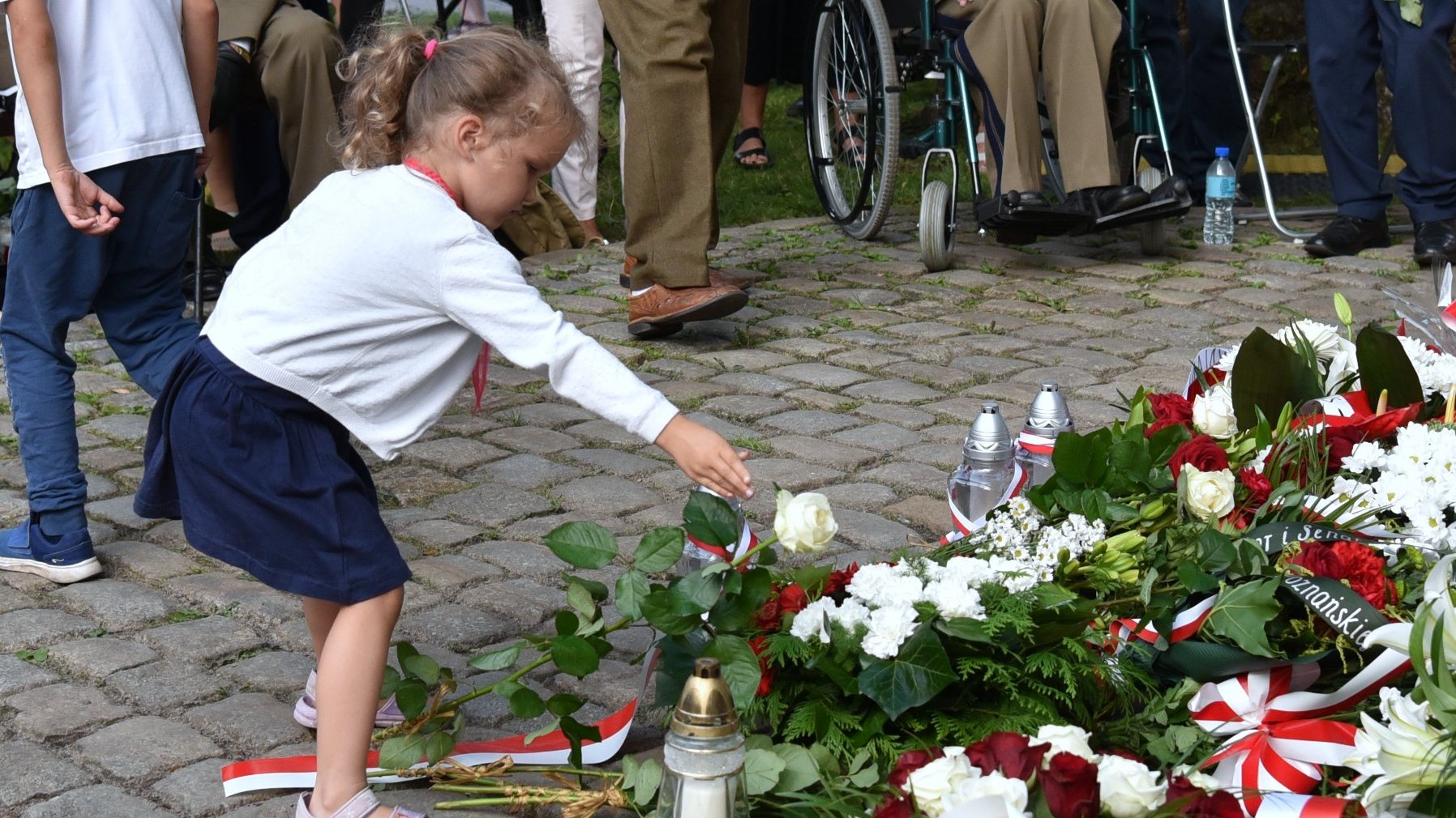 Na zdjęciu mała dziewczynka składająca kwiat