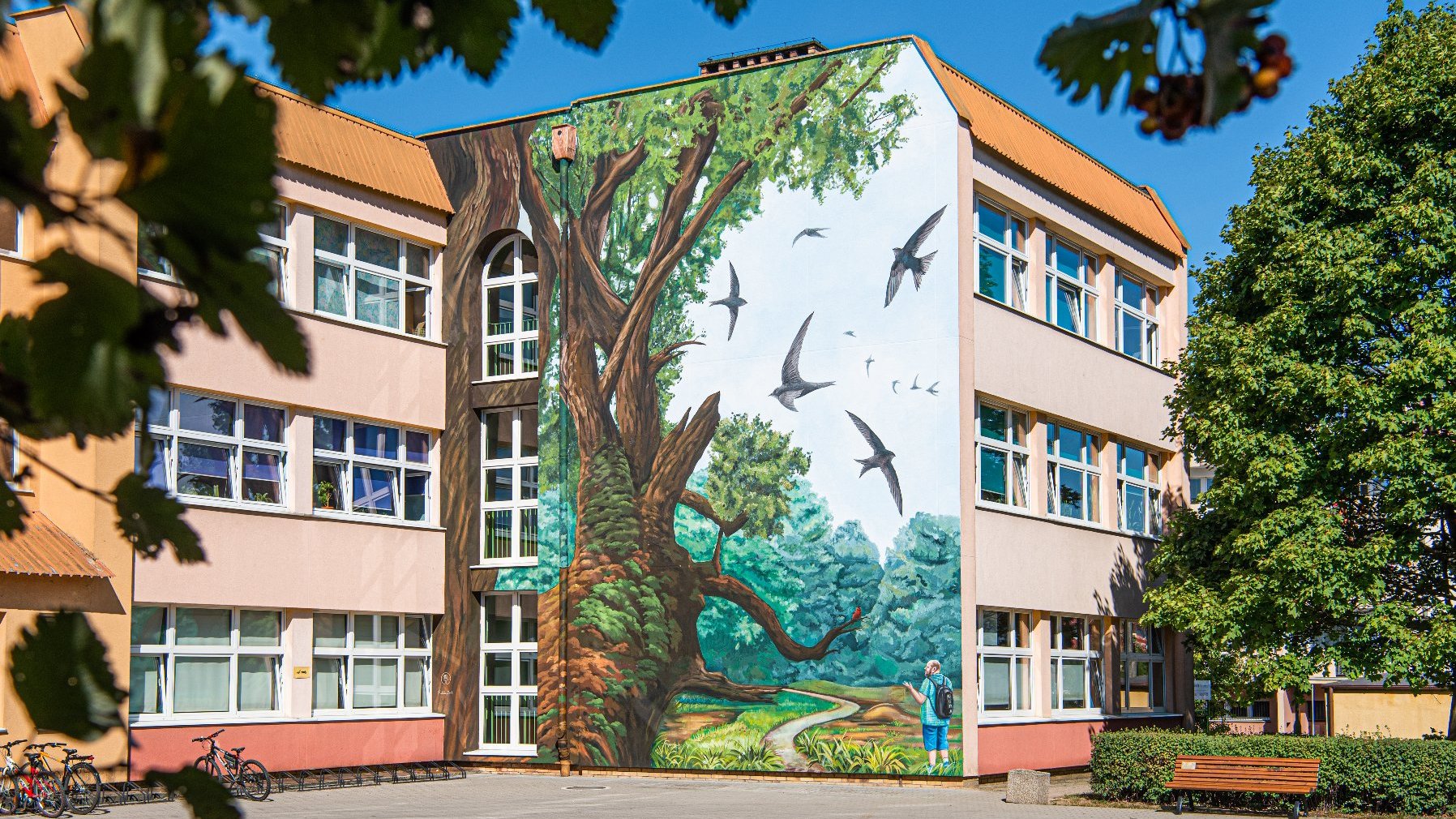 Galeria zdjęć przedstawiająca mural na szkole z różnej odległości oraz perspektywy