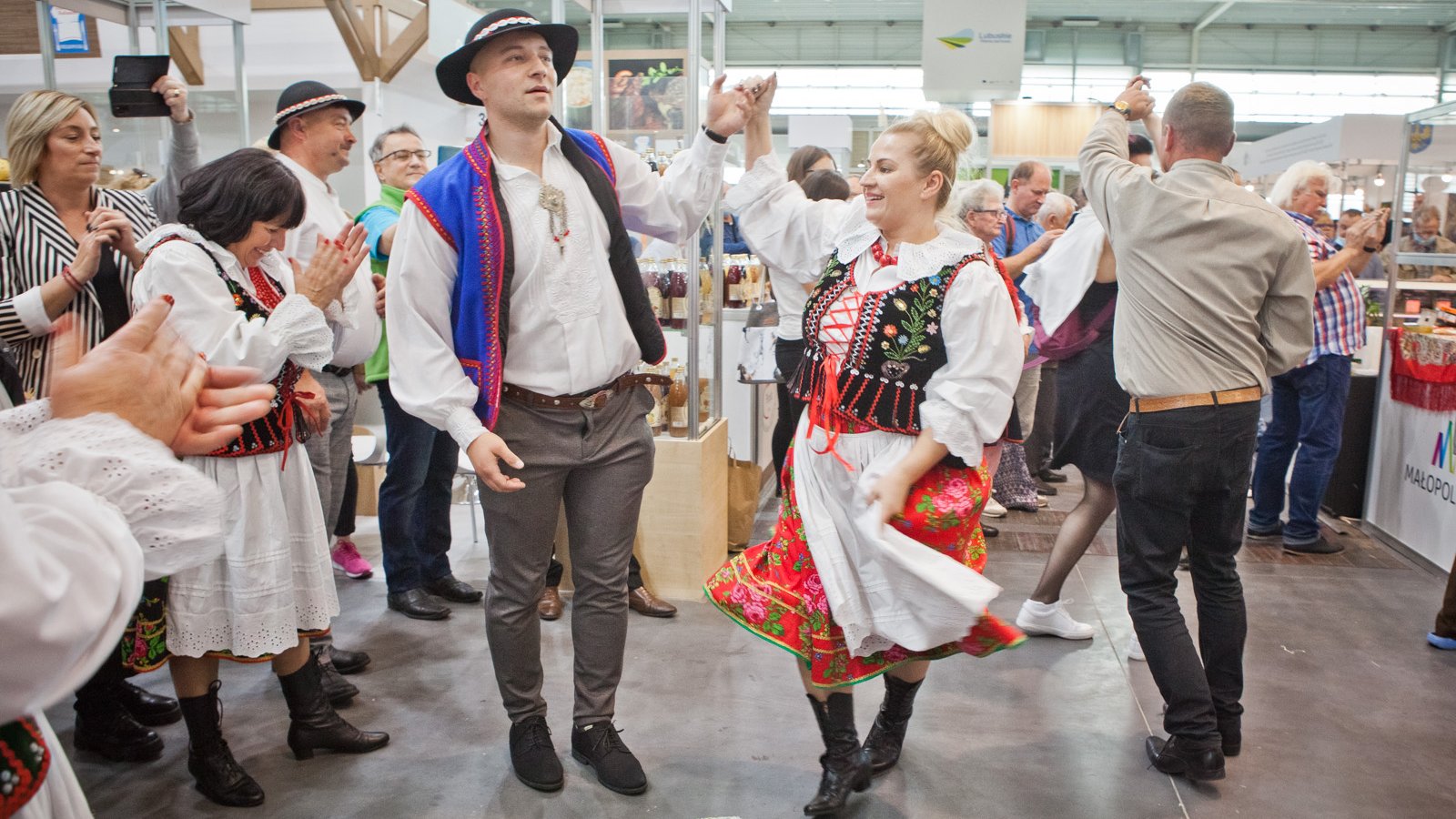 Na zdjęciu para tańcząca w ludowych strojach, dookoła inni ludzie