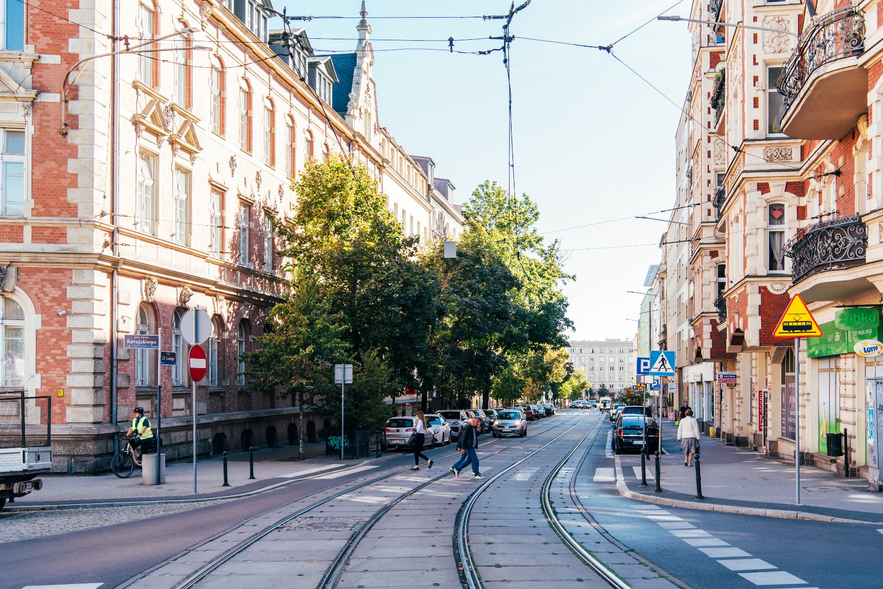 Na zdjęciu ulica 23 Lutego, w centrum torowisko, widać przechodniów i budynki - grafika artykułu