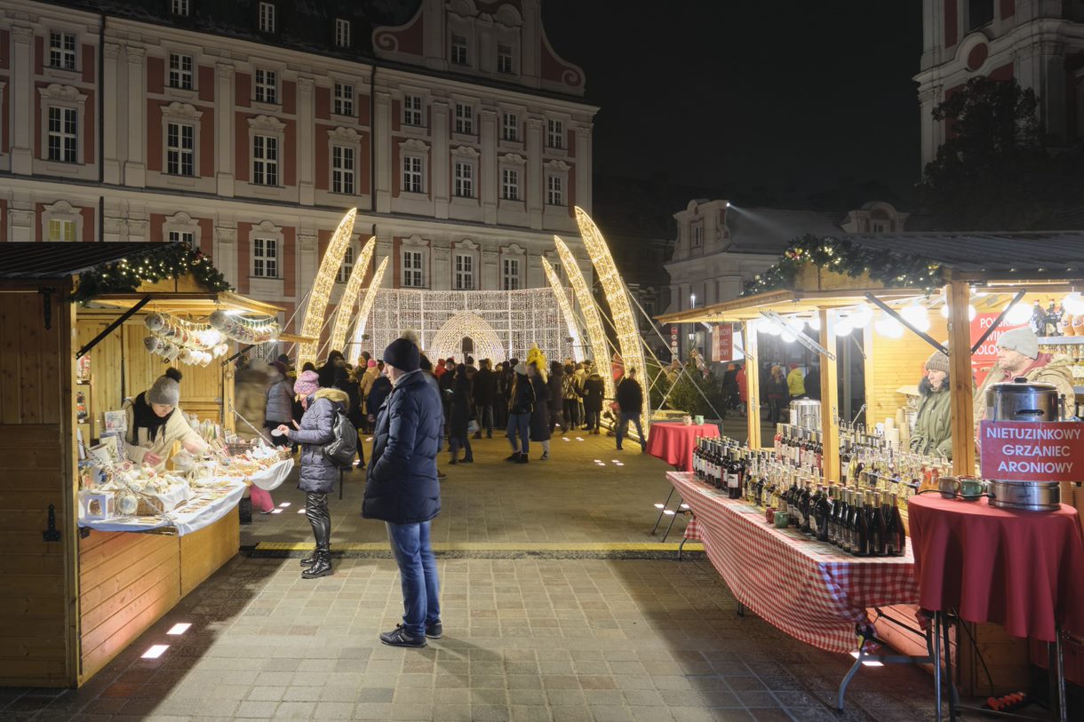 Na zdjęciu ludzi odwiedzający stoiska na jarmarku, w tle iluminacje - grafika artykułu