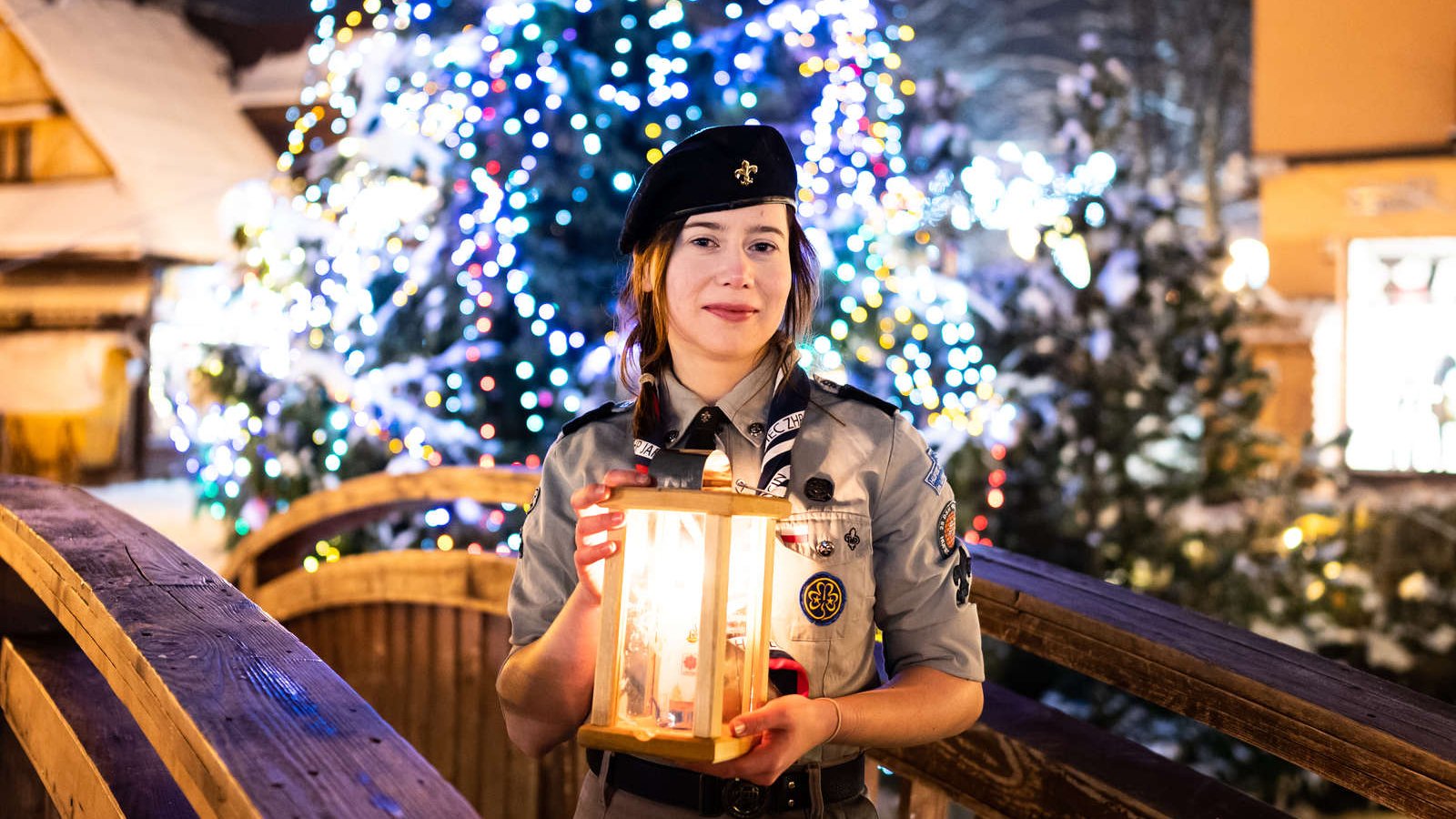 Harcerka trzymająca w dłoniach lampion z płonącą świeczką.