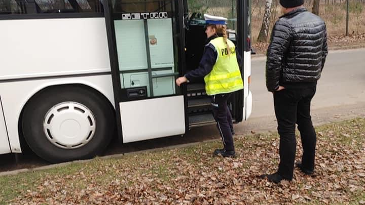 Na zdjęciu policjantka wchodząca do autobusu, obok stoi kierowca