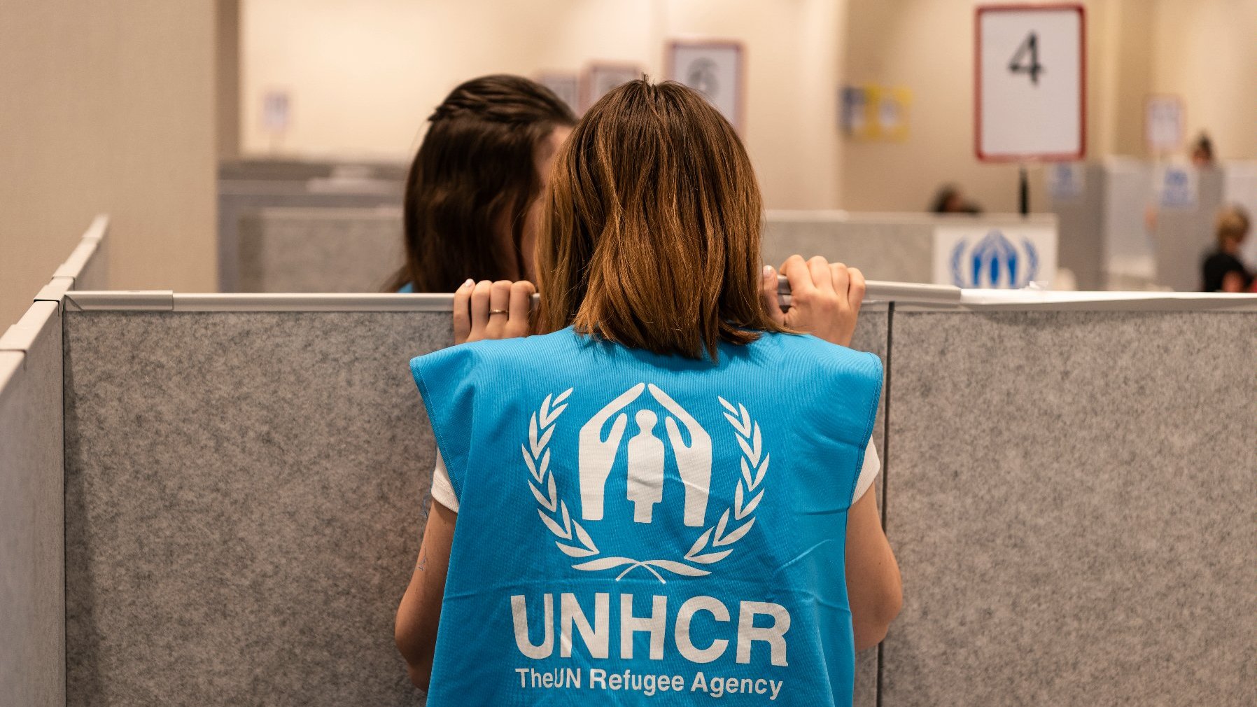 Na zdjęciu pracownice UNHCR w błękitnych kamizelkach, rozmawiają ze sobą