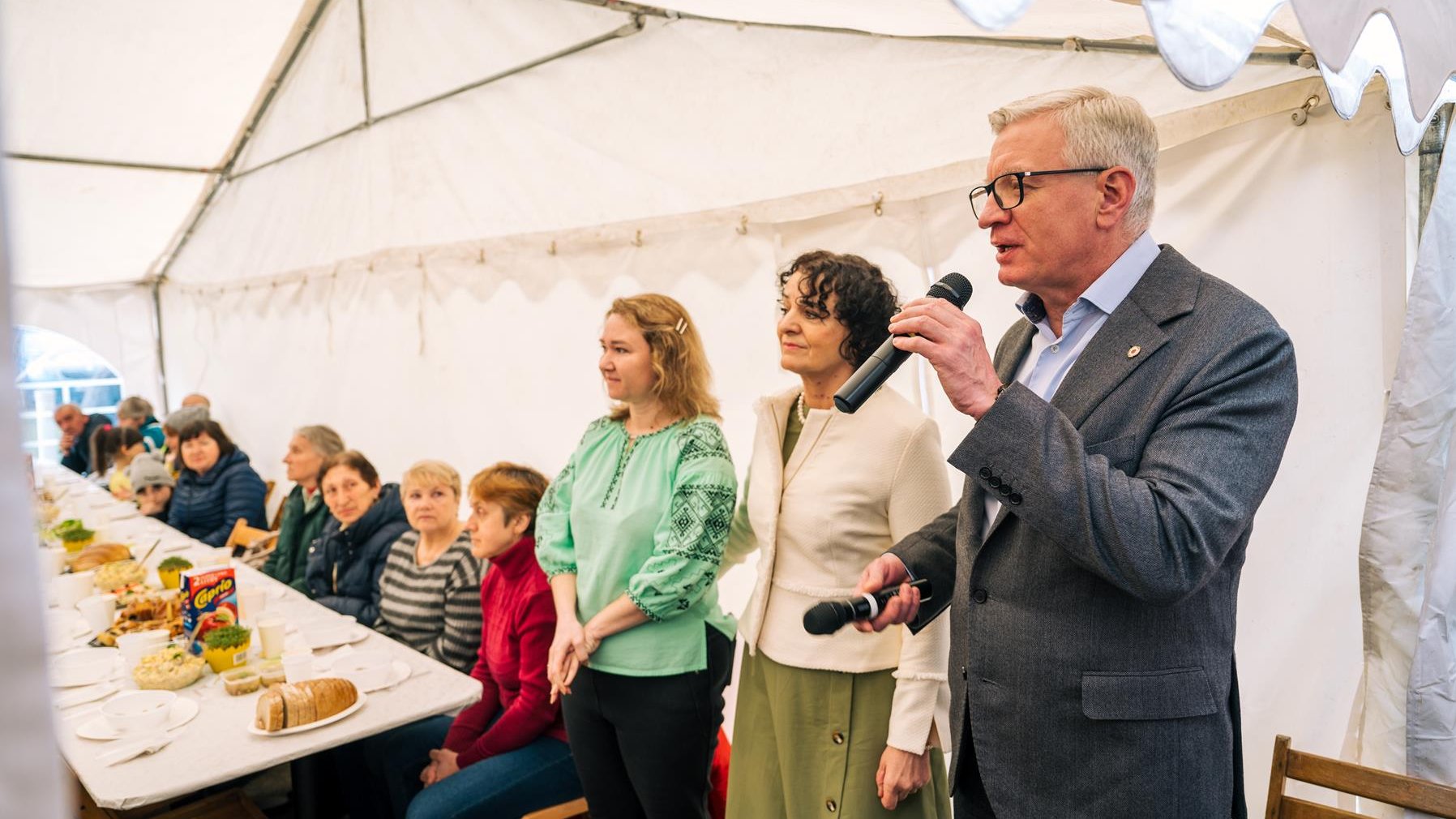 Na zdjęciu Jacek Jaśkowiak z mikrofonem w ręku, obok stojące kobiety