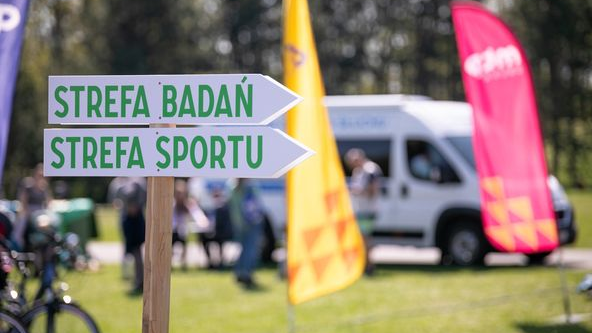 Na zdjęciu piknik, na pierwszym planie drogowskaz z napisem: strefa badań, strefa sportu