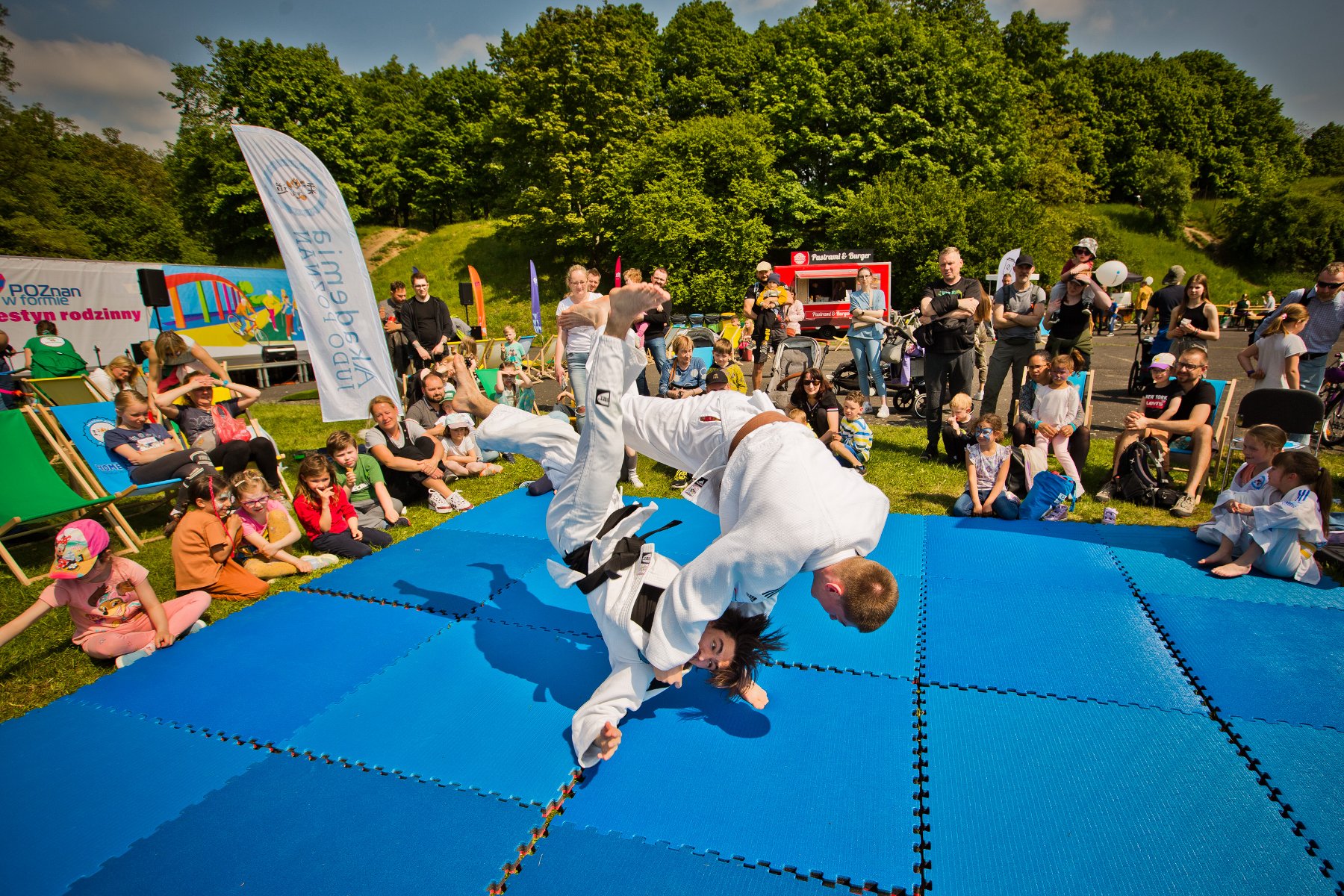 Na zdjęciu chłopcy ćwiczący judo w parku - grafika artykułu