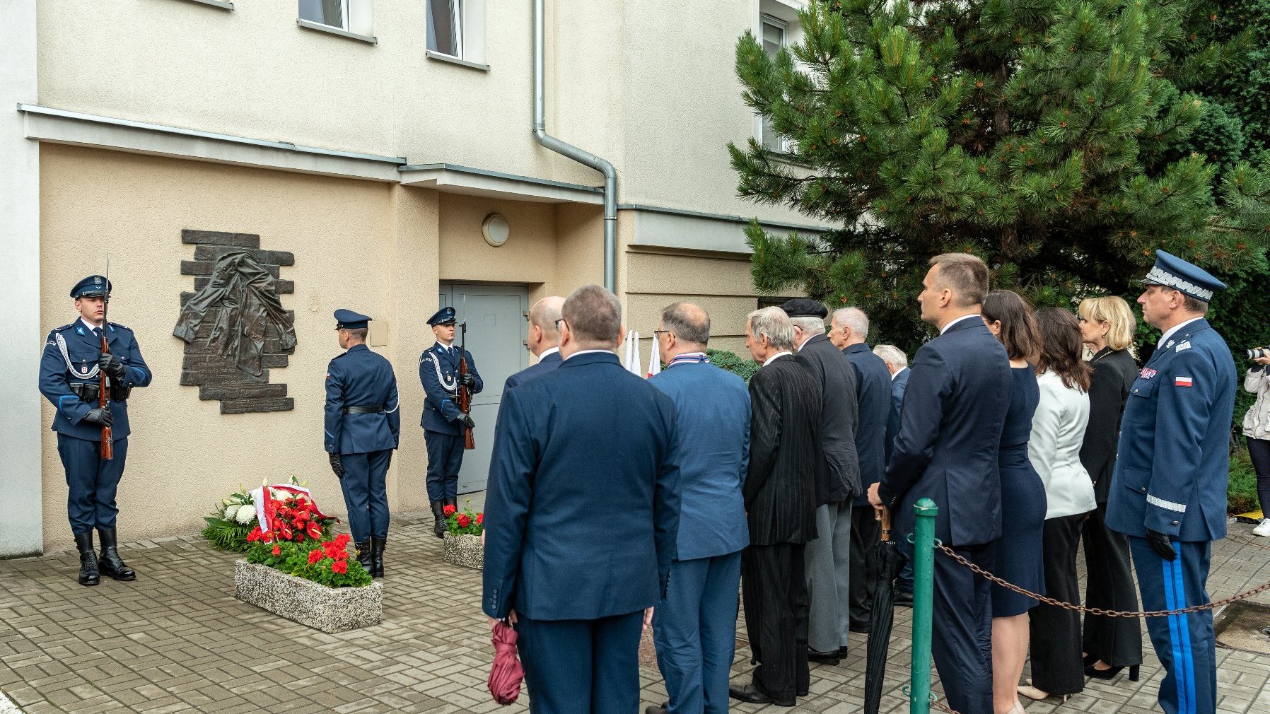 Na zdjęciu policjanci składają kwiaty pod komendą policji