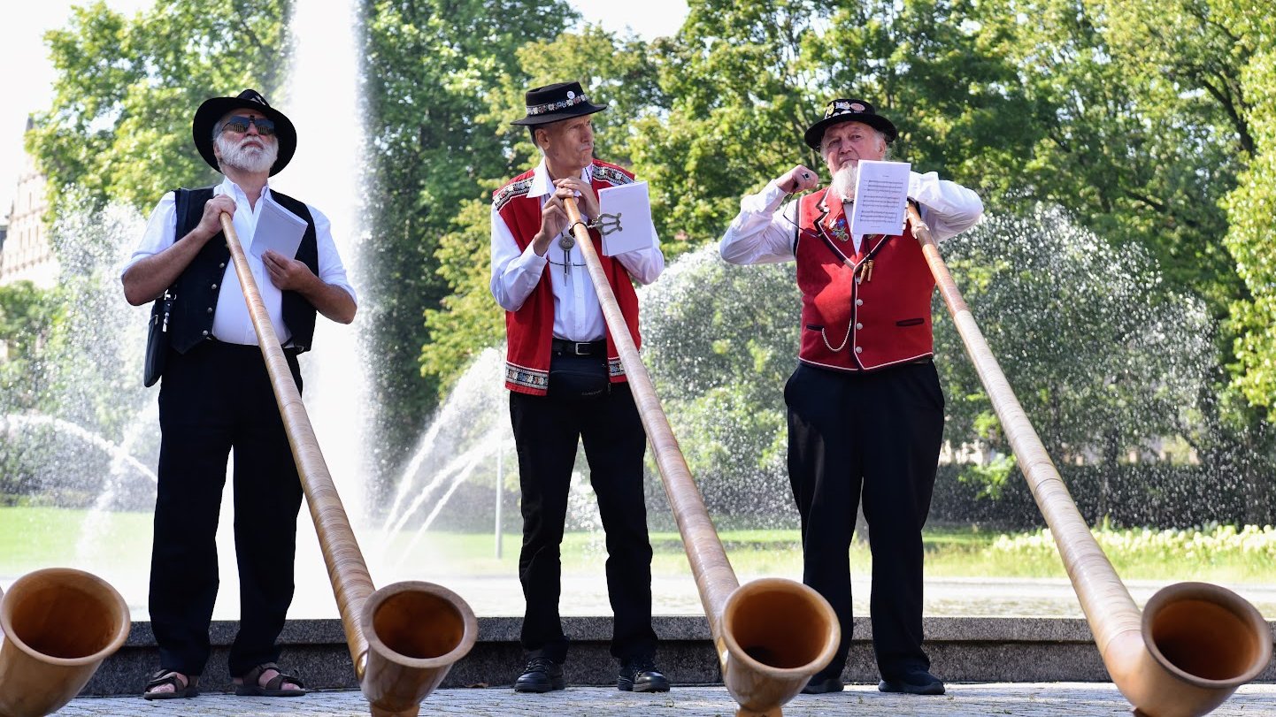 Na zdjeciu trzech muzyków trzymających rogi alpejskie