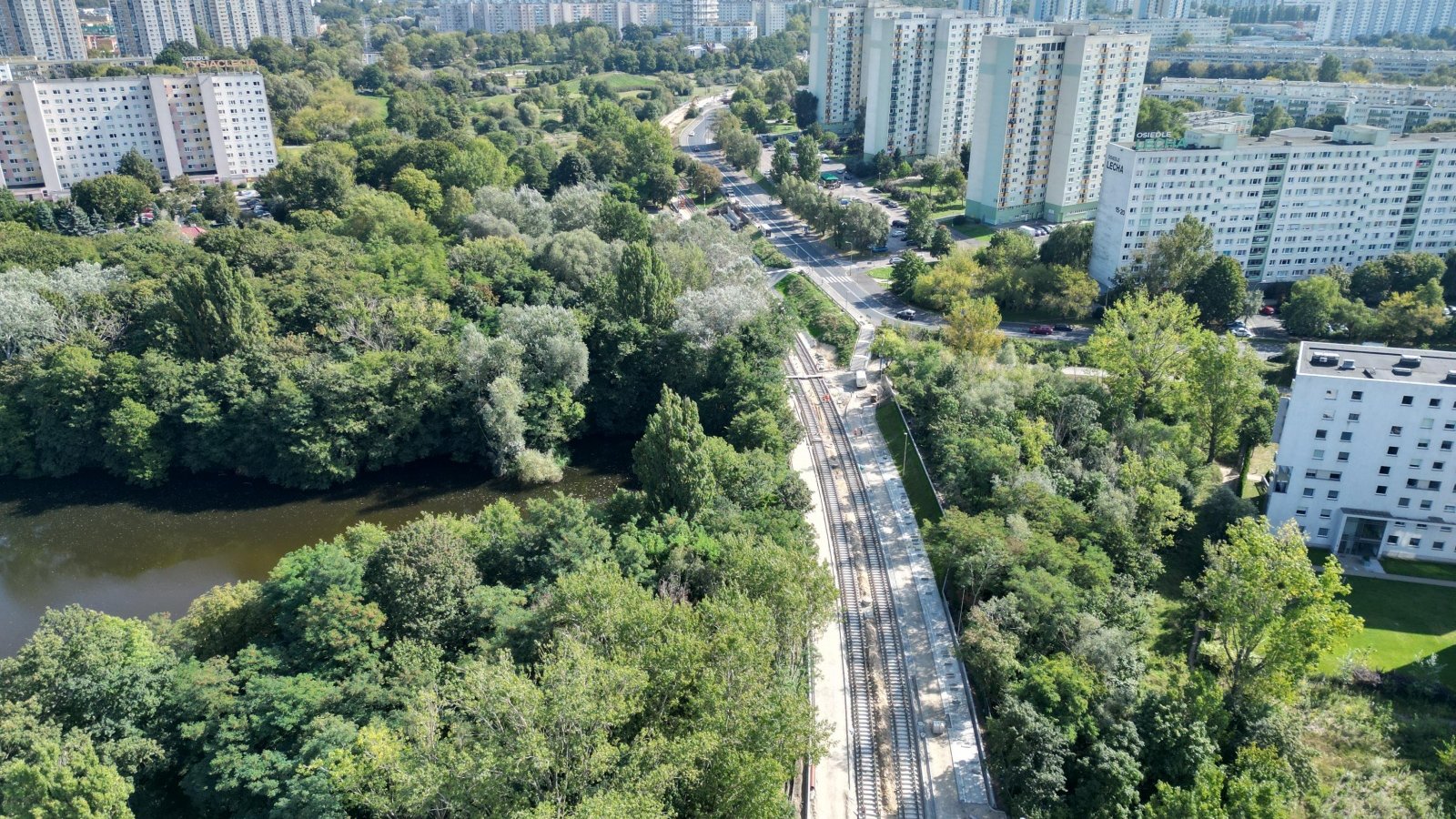 Galeria zdjęć przedstawia z lotu ptaka trasę tramwajową pokrytą zielenią.