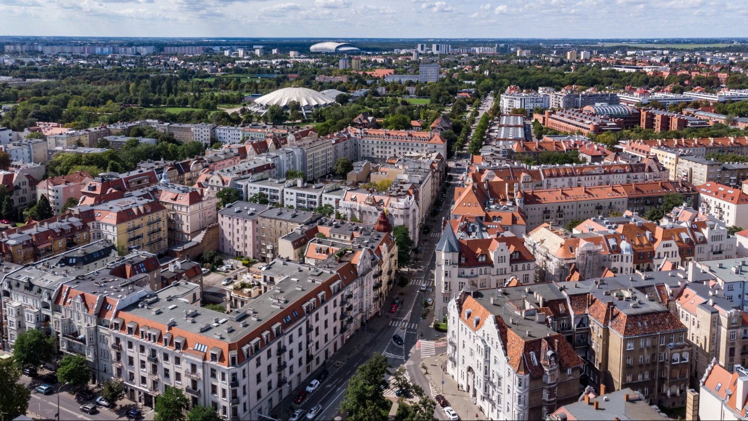 Na zdjęciu panorama Poznania z lotu ptaka, widać kamienice, w tle Arenę