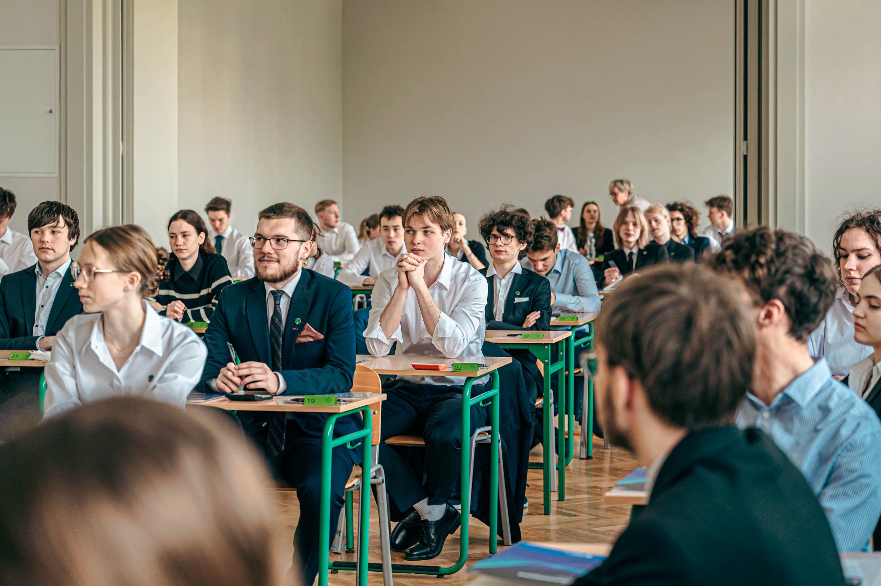 Zdjęcie przedstawia maturzystów siedzących w ławkach. - grafika artykułu