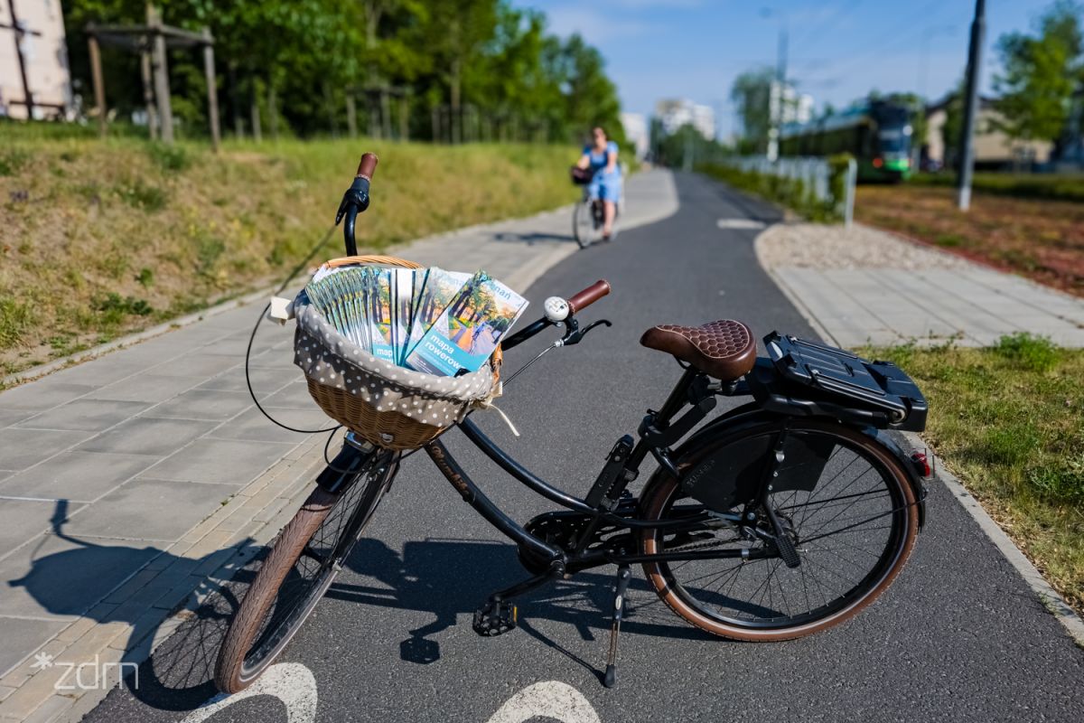 Stojący rower, w którym przednim bagażniku włożone są mapy rowerowe - grafika artykułu