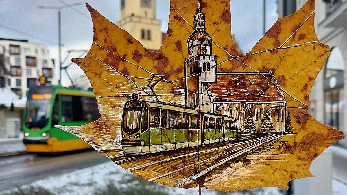 Na zdjęciu klonowy liść, na nim narysowany poznański tramwaj i kościół