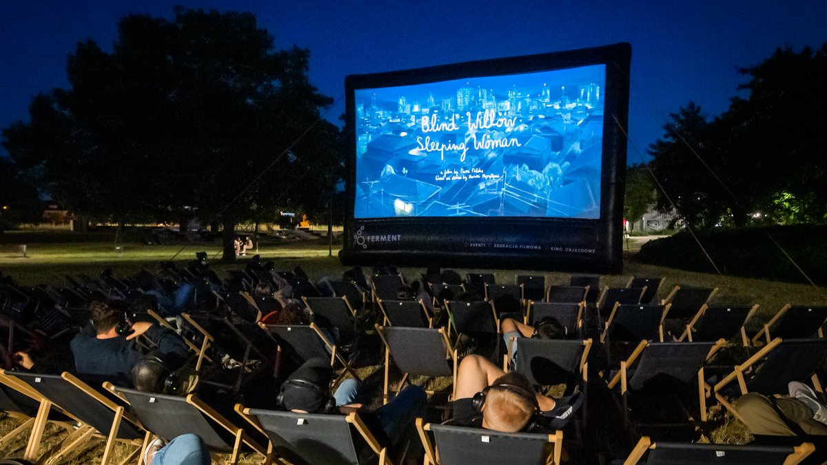 Zdjęcie przedstawia ludzi oglądających film w plenerze.