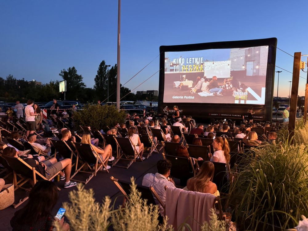 Kino plenerowe, fot. Mateusz Tomasik Ludzie oglądają film pod gołym niebem. Zmierzcha.