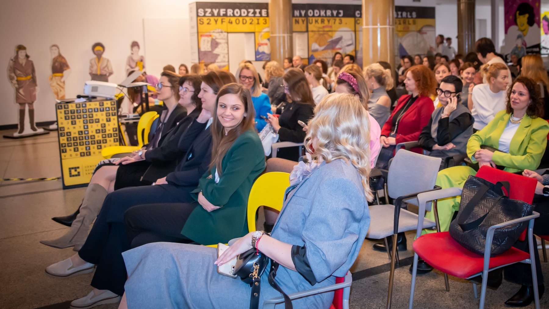 Grafika promująca konferencję.Zdjęcie przedstawiające siedzące kobiety