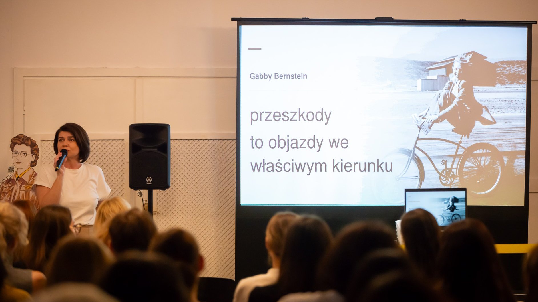 Grafika promująca konferencję.Zdjęcie przedstawiające przemawiającą kobietę