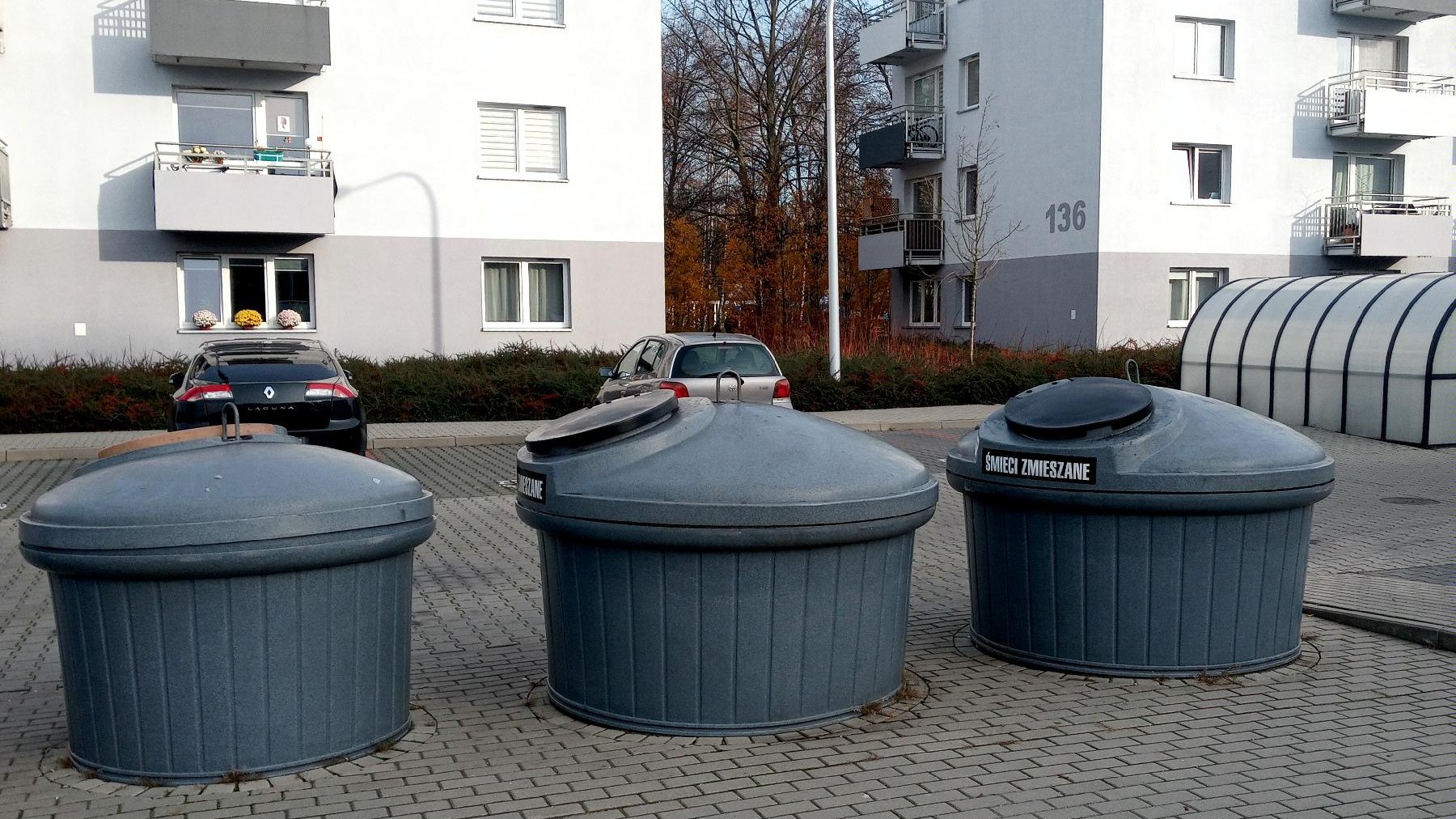 Na zdjęciu kosze na śmieci. W tle zabudowania.