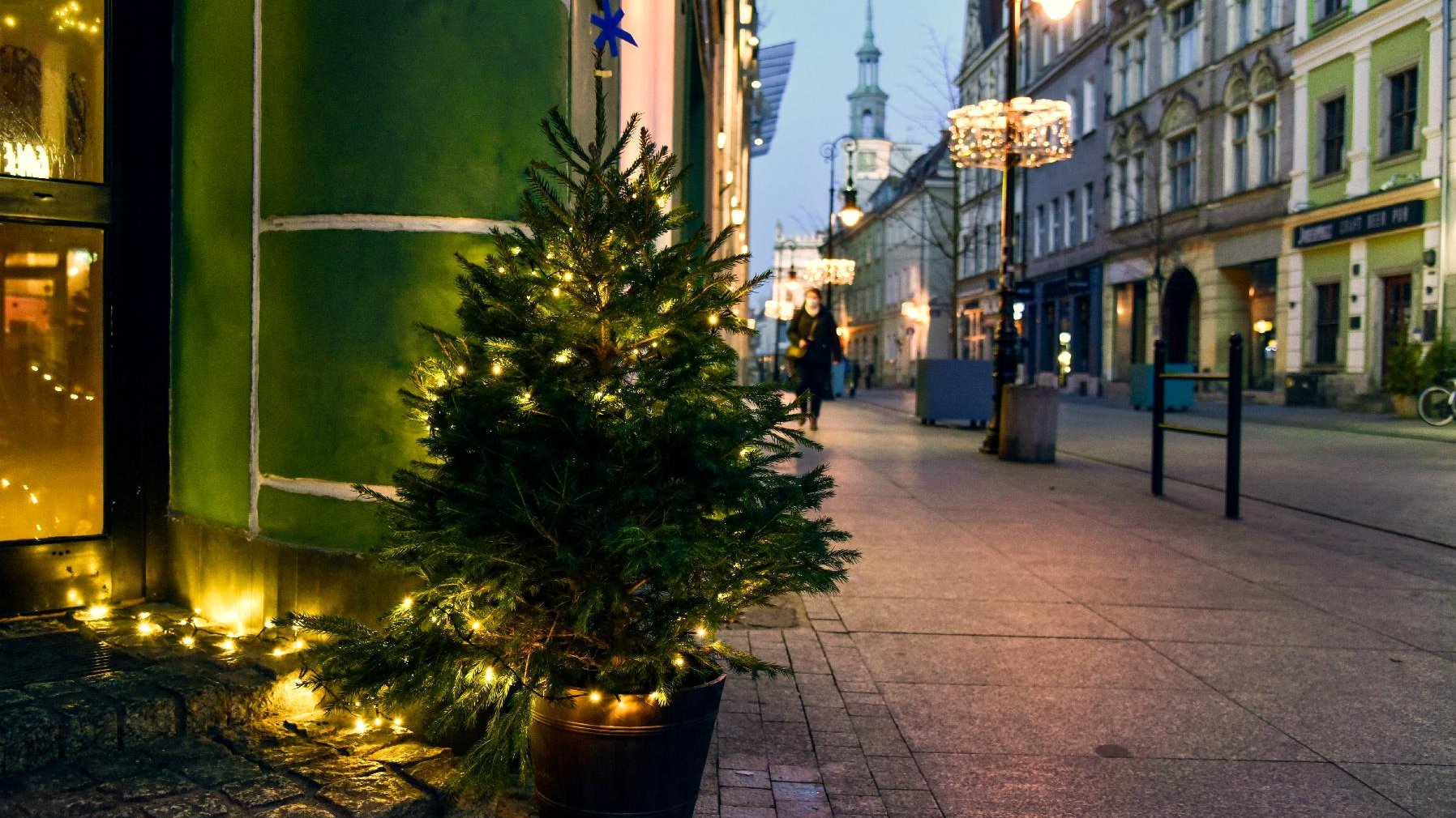 Przystrojona w światełka i logo Miasta Poznania choinka. W tle ulica Wrocławska. W oddali wieża Ratusza.