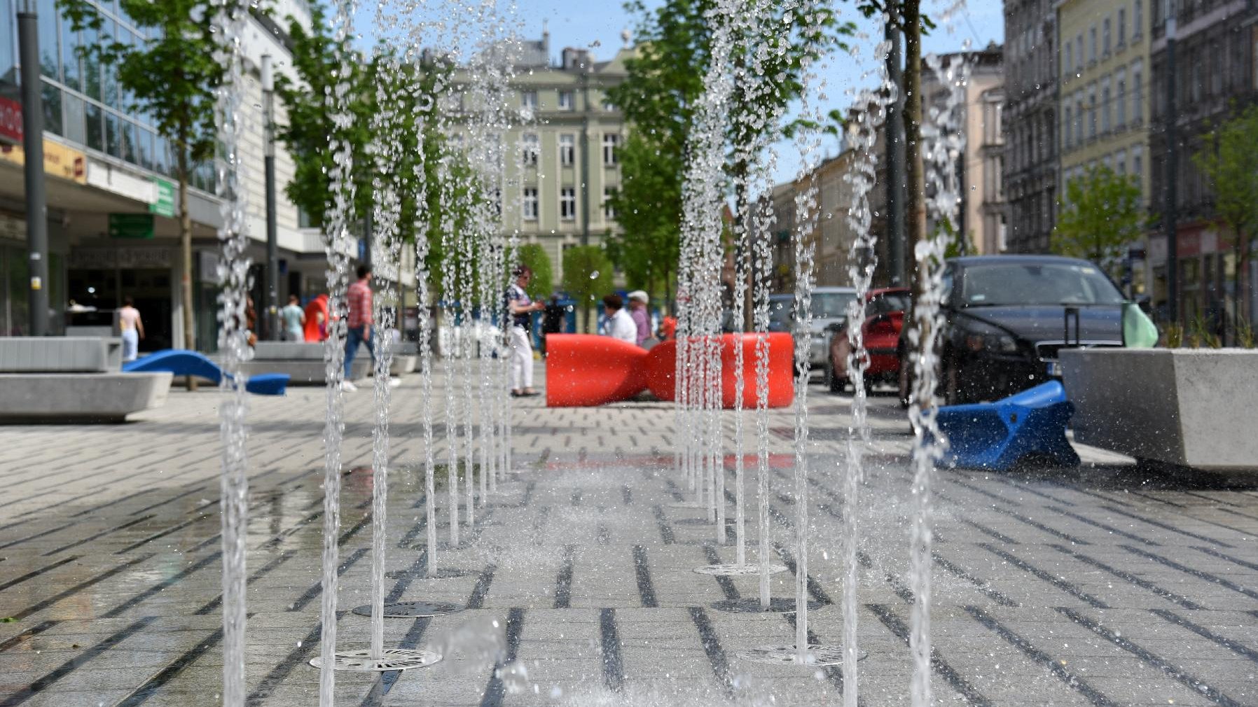 Na zdjęciu ul. Święty Marcin, w centrum fontanna, po jej bokach drzewa, w tle kamienica