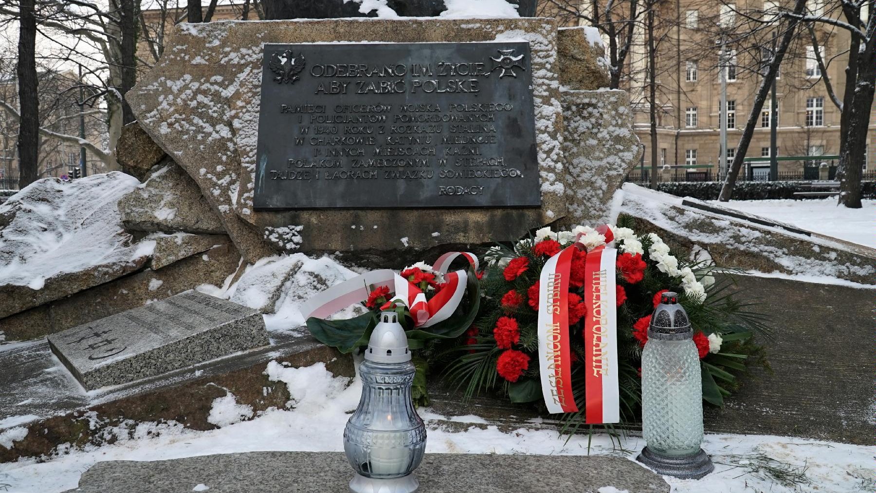 Na zdjęciu pokryty śniegiem pomnik, pod nim wiązanka i znicze