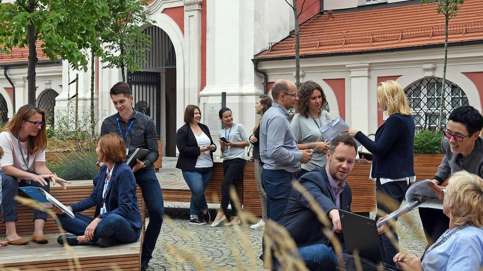 Dziedziniec Urzędu Miasta Poznania - na zdjęciu widzimy wielu ludzi, którzy połączyli się w małe grupki, śmieją się i rozmawiają. - grafika artykułu