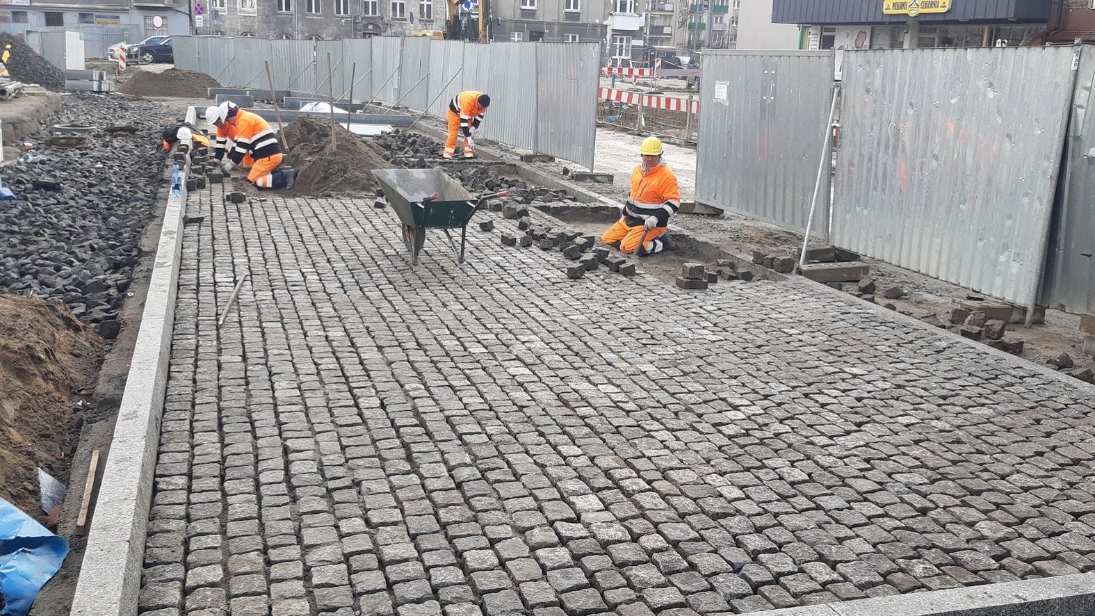 Na zdjęciu Rynek Łazarski - na pierwszym planie nowa nawierzchnia, w tle - układający ją robotnicy