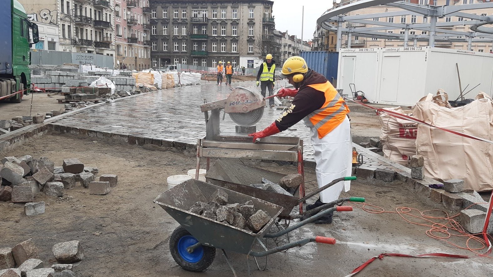 Na zdjęciu Rynek Łazarski - na pierwszym planie robotnik przy pile tarczowej, w tle konstrukcja zadaszenia oraz kamienice