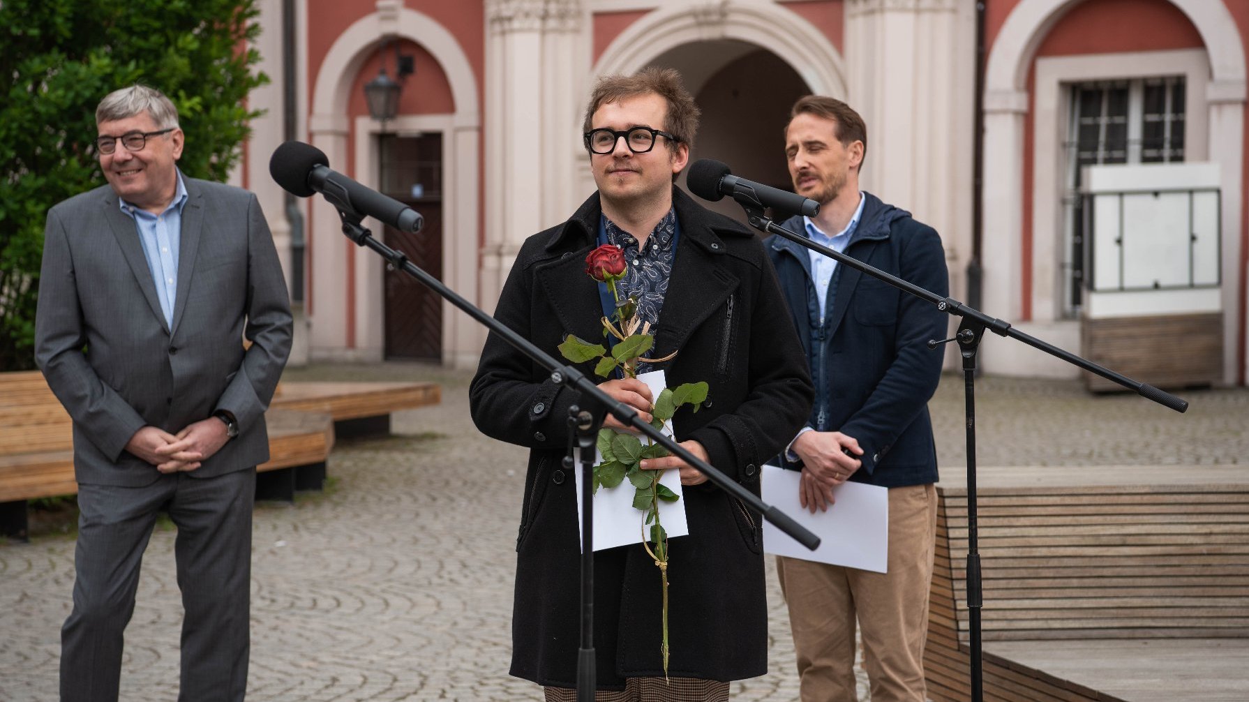 Galeria zdjęć z uroczystości wręczenia stypendiów - jeden z laureatów trzyma w ręku czerwoną różę, obok stoją Grzegorz Ganowicz i Grzegorz Jura.