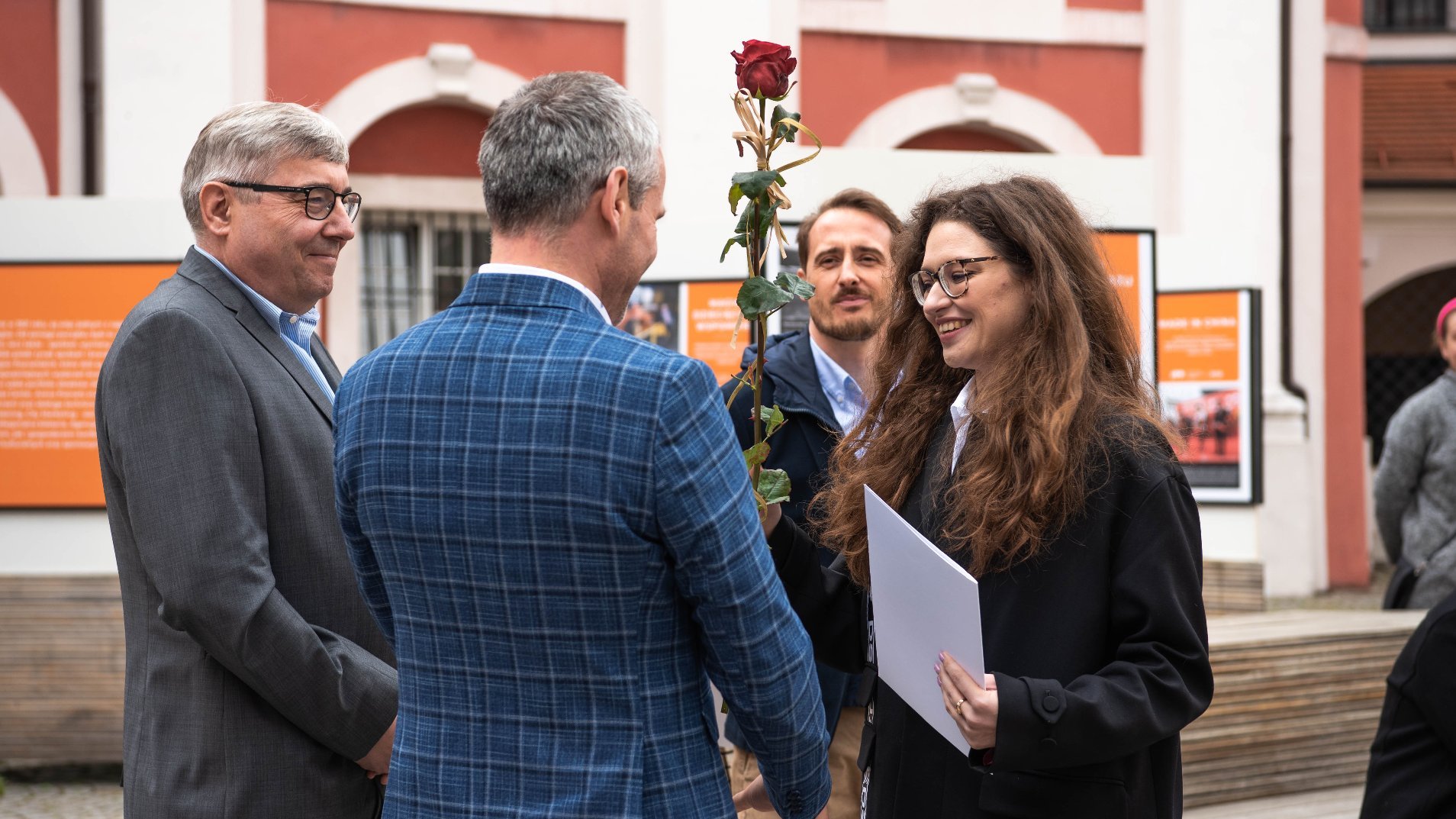 Galeria zdjęć z uroczystości wręczenia stypendiów - Grzegorz Ganowicz i Jędrzej Solarski wręczają wyróżnienie i czerwoną różę jednej z laureatek.