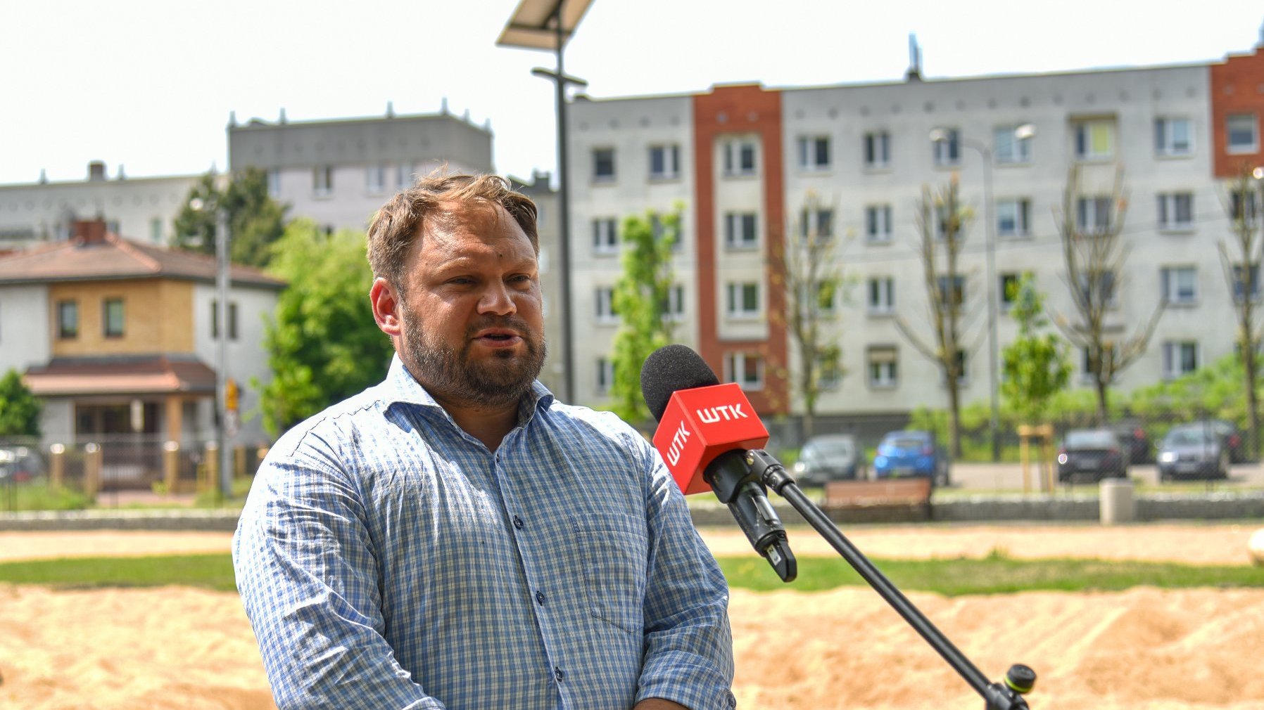 Zdjęcie przedstawia radnego Tomasza Stachowiaka przed mikrofonem.