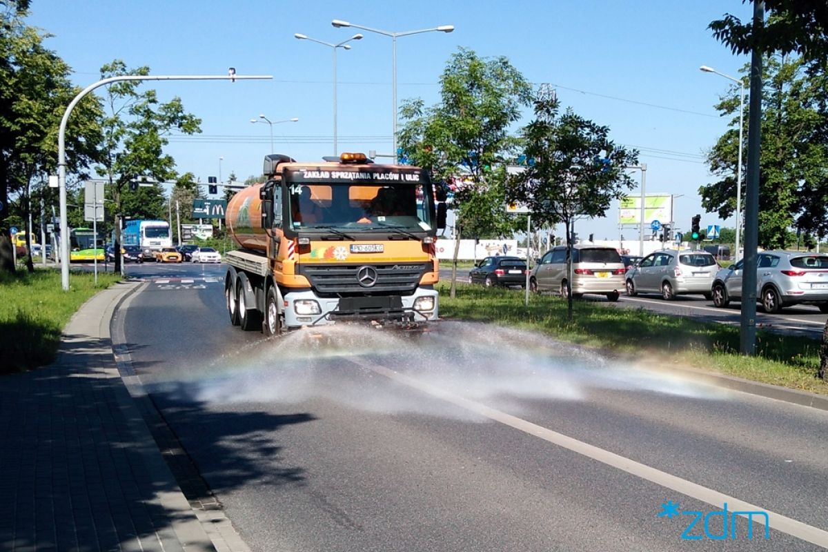 Zdjęcie przedstawia samochód polewaczkę, jadący po ulicy. - grafika artykułu