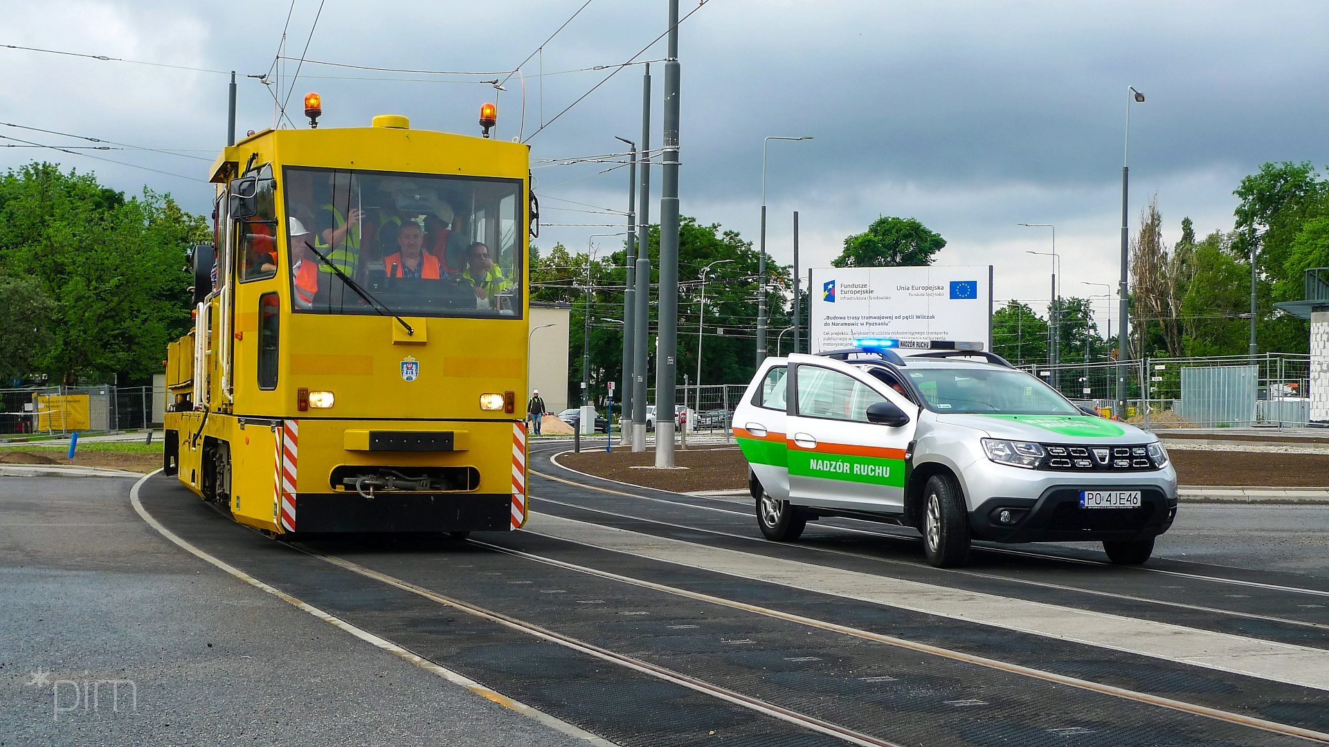 Na zdjęciu żółty pojazd testowy na torowisku, obok samochód Nadzoru Ruchu