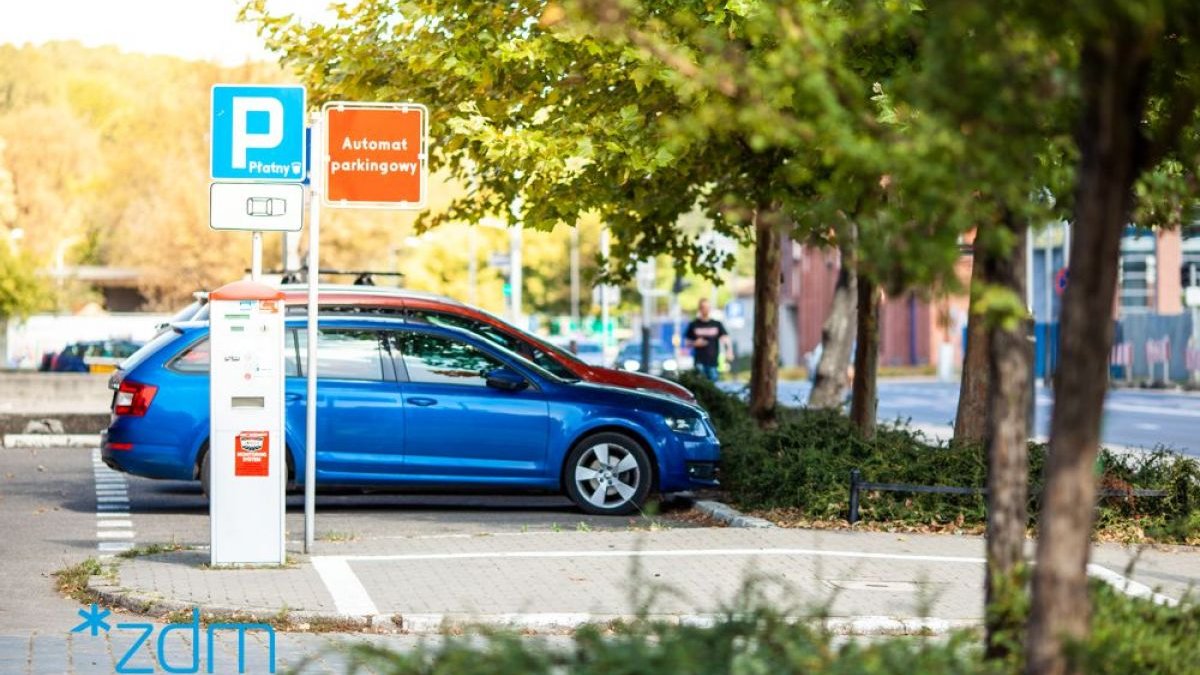 Parkomat i samochód zaparkowany w strefie płatnego parkowania