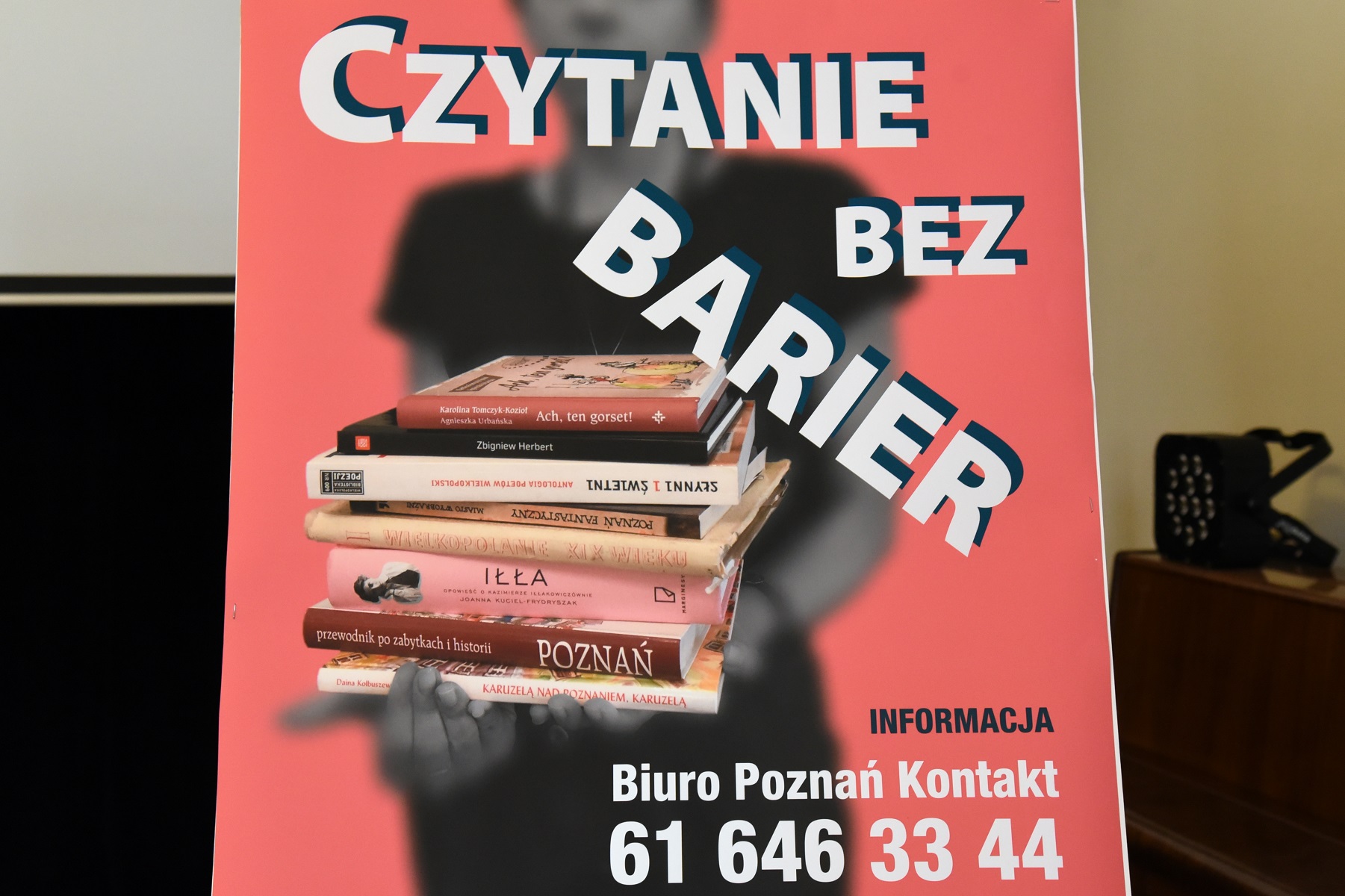 Plakat "Czytania bez barier" - rozmyta postać trzymająca wyraźne książki, na pierwszym planie nazwa usługi - grafika artykułu