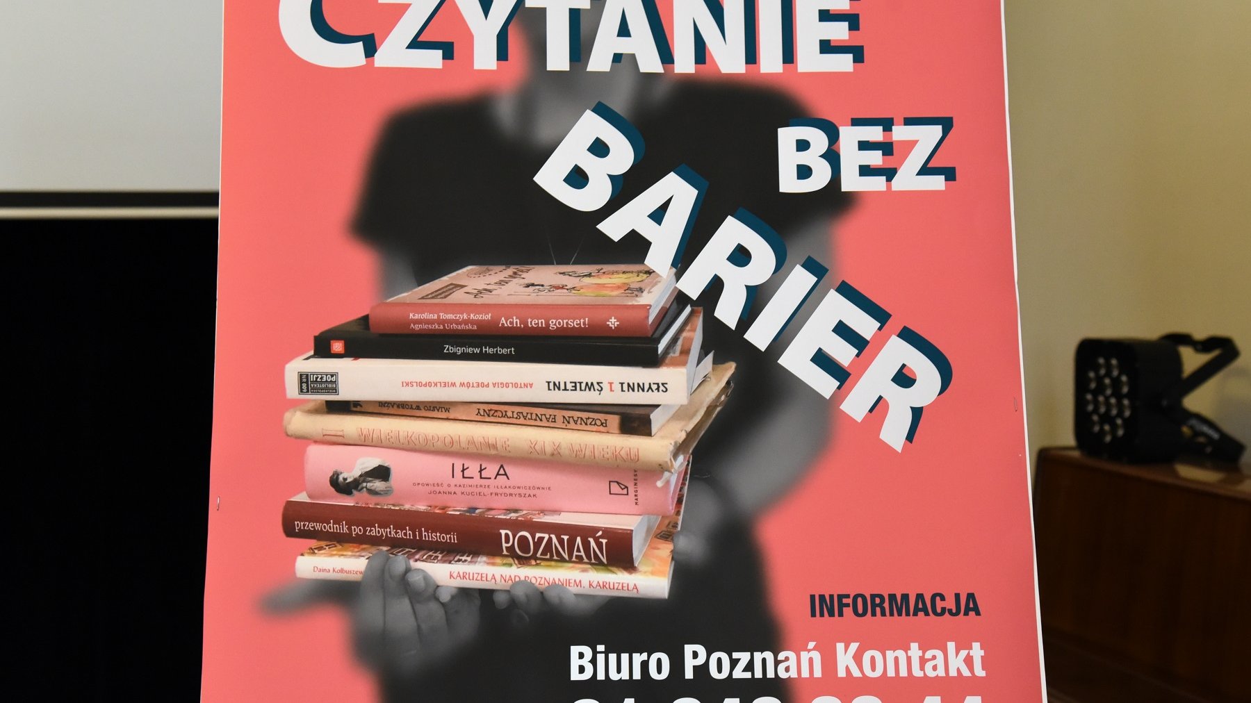 Plakat "Czytania bez barier" - rozmyta postać trzymająca wyraźne książki, na pierwszym planie nazwa usługi