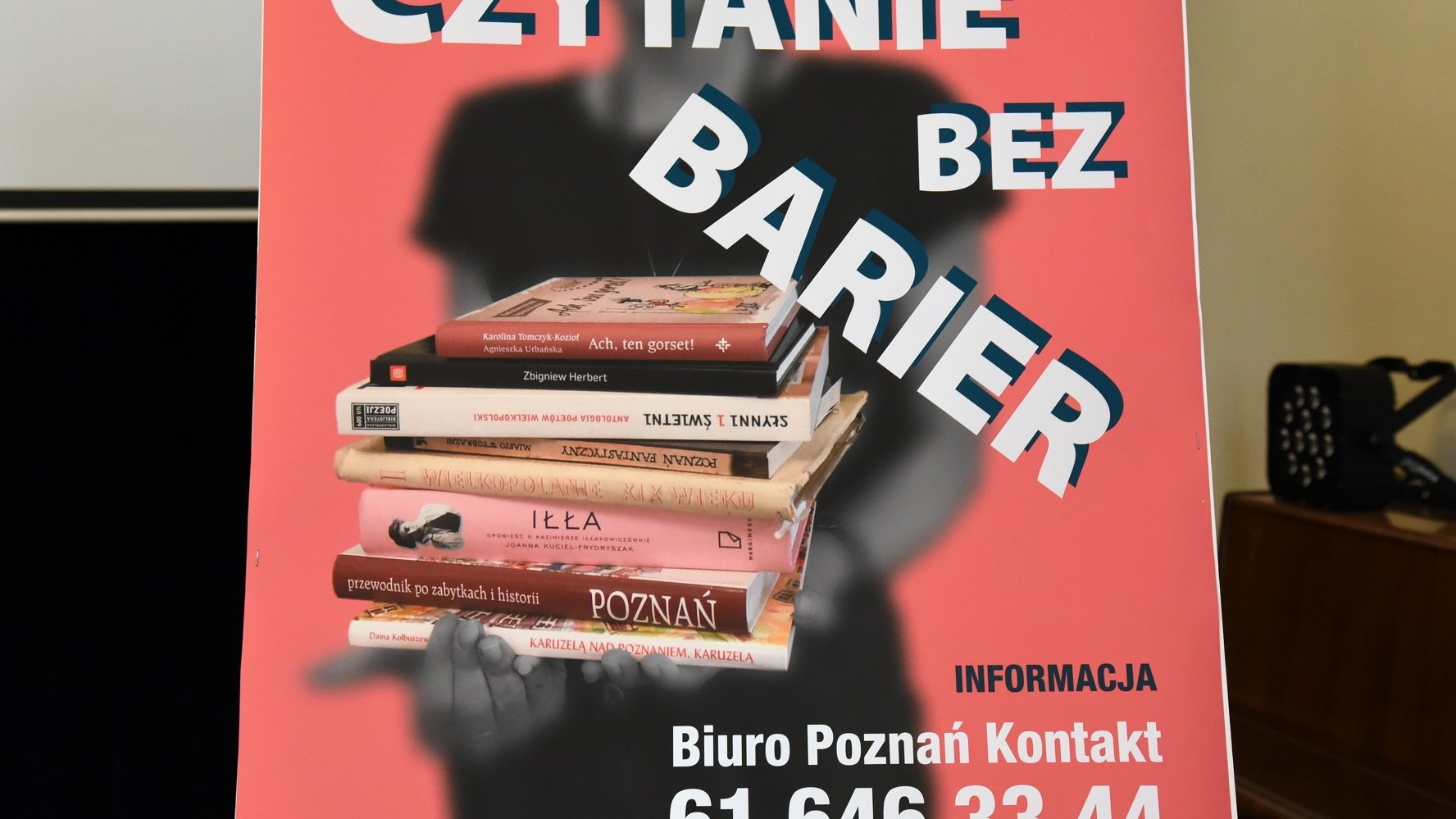 Plakat "Czytania bez barier" - rozmyta postać trzymająca wyraźne książki, na pierwszym planie nazwa usługi