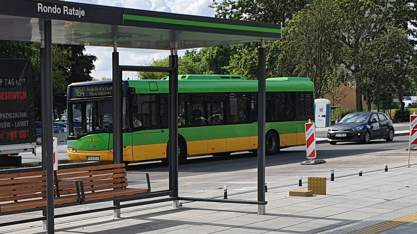 Rondo Rataje, na pierwszym planie wiata przystankowa, za nią widać autobus i drzewa