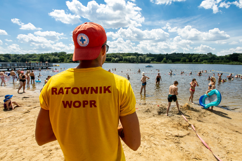 Ratownik nad jeziorem. W tle jezioro i kąpiący się ludzie. - grafika artykułu