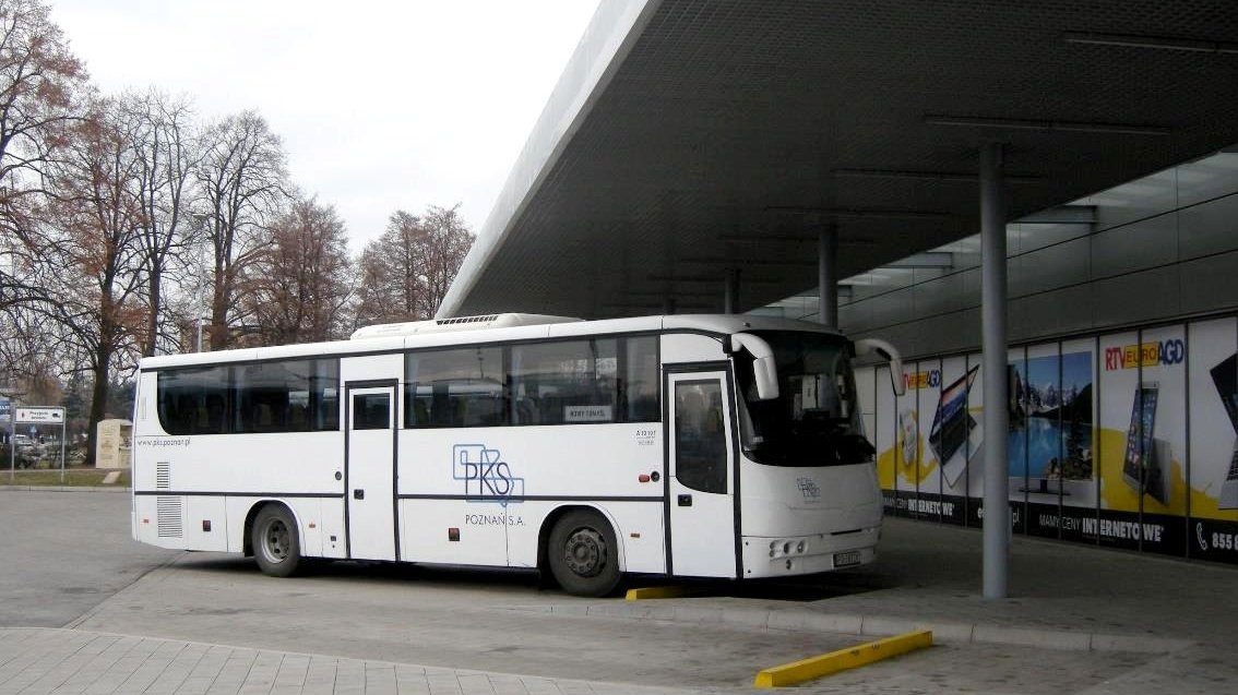 Zdjęcie przedstawia autobus stojący pod wiatą przystankową.