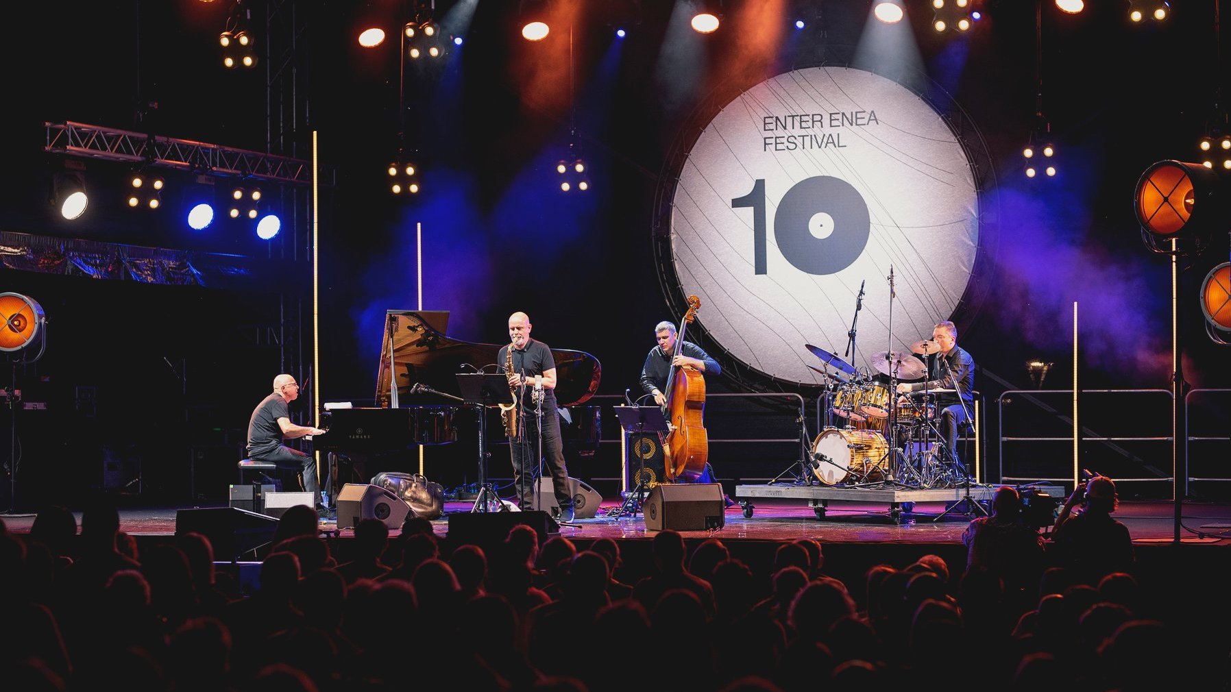 Zdjęcie przedstawia muzyków na scenie. W tle widać napis "Enter Enea Festival" oraz liczbę 10.