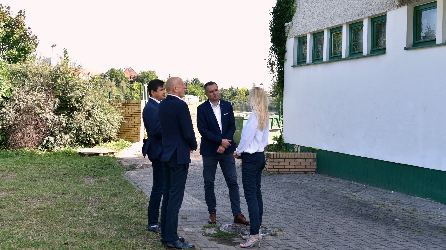 Zdjęcie przedstawia wiceprezydenta Wiśniewskiego, pracowników Wydziału Oświaty oraz dyrektorkę szkoły, stojących obok budynku.