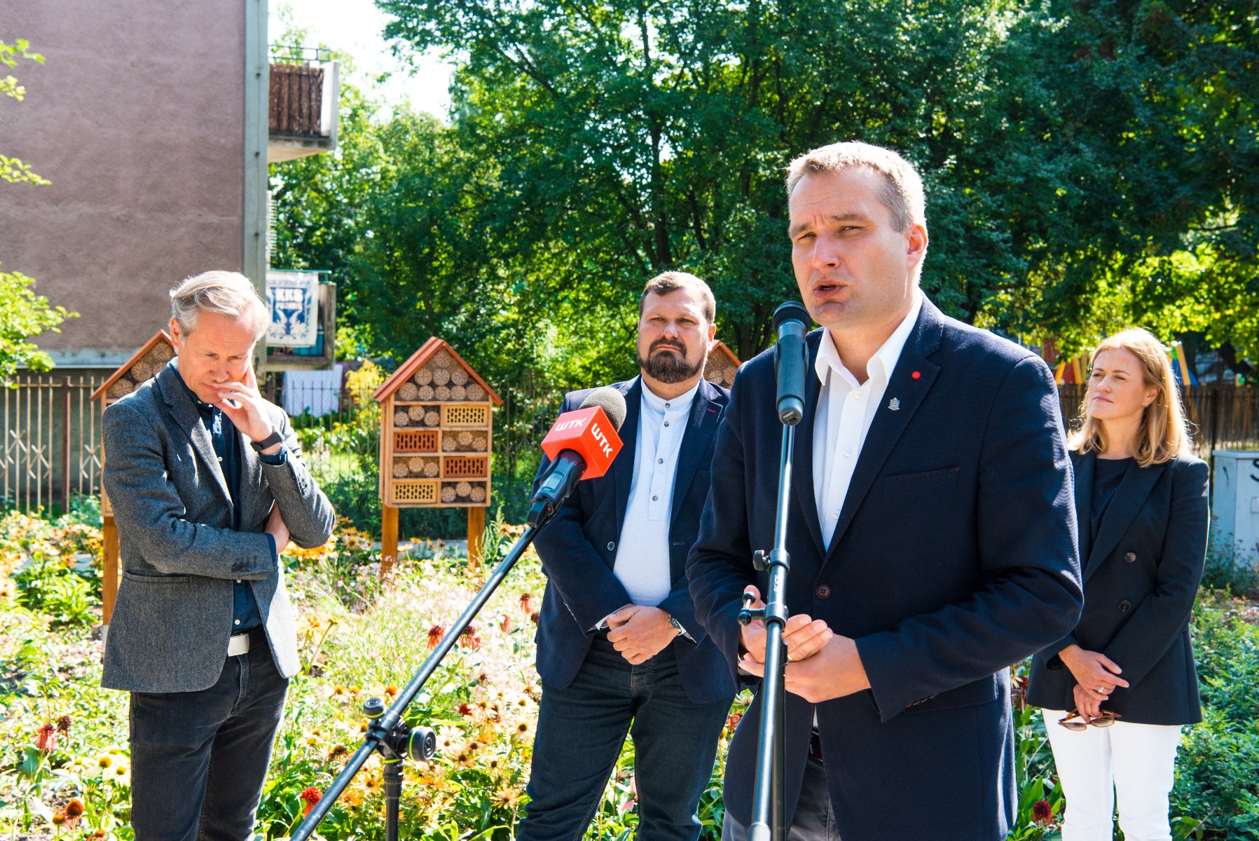 Galeria zdjęć przedstawia konferencję prasową na skwerze oraz sam skwer z zielenią i domkami dla owadów. - grafika artykułu