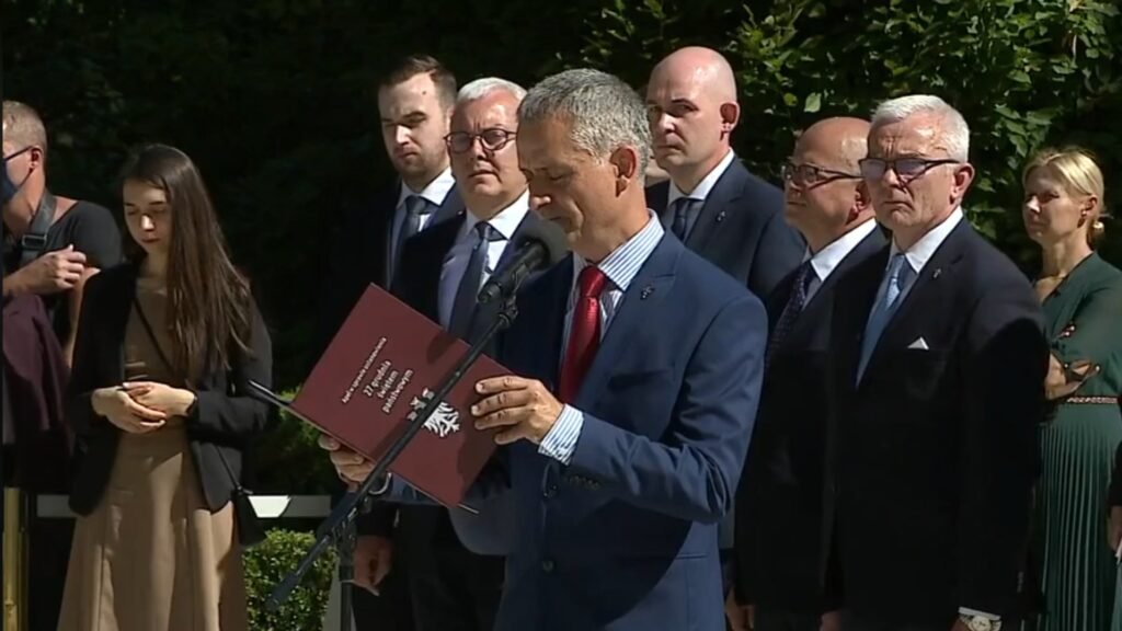 Zdjęcie przedstawia grupę osób stojącyh w ogrodzie Pałacu Prezydenckiego.